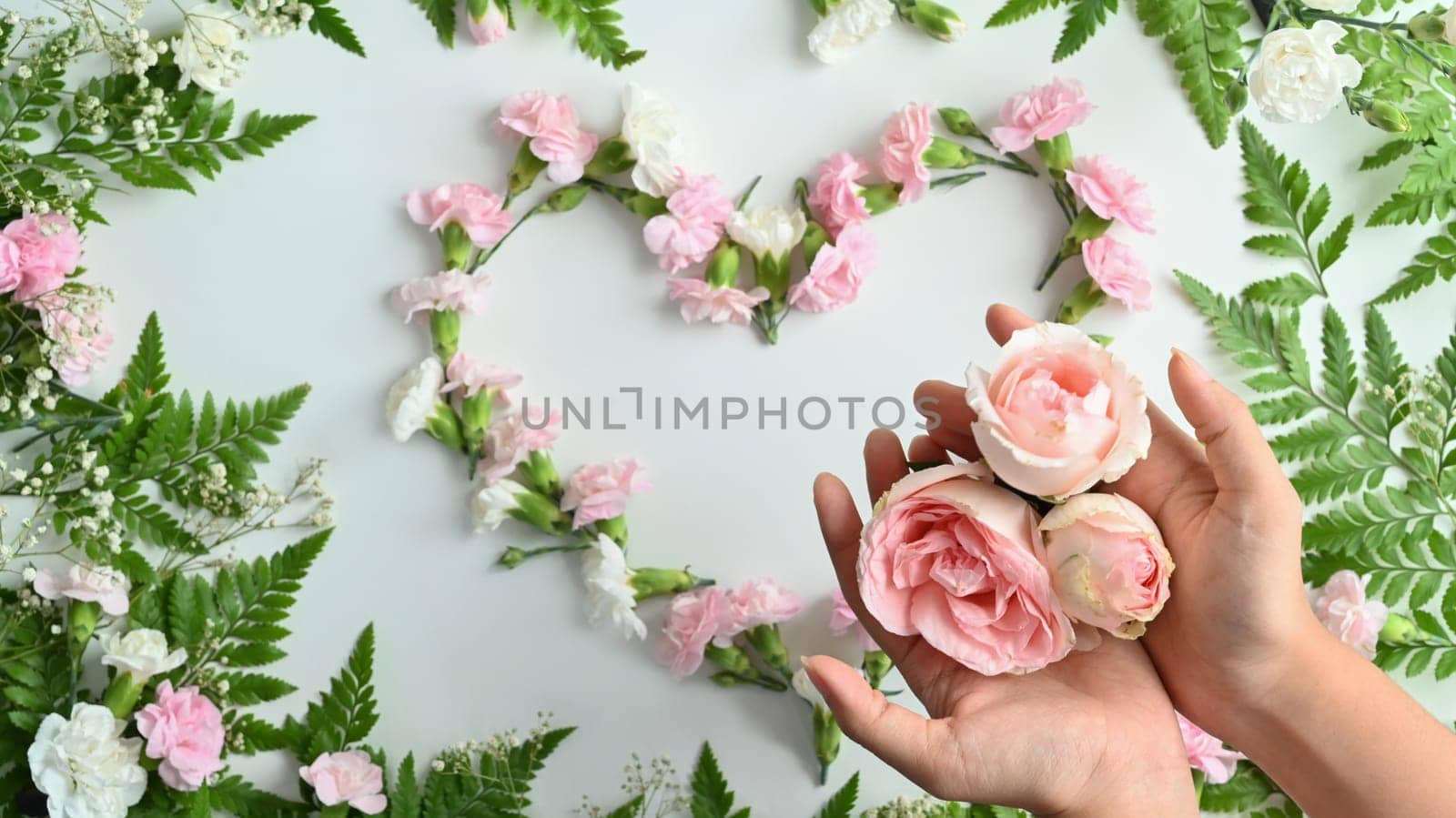 Hands holding pink rose with flowers patterns blooming for wallpaper or wedding card background by prathanchorruangsak