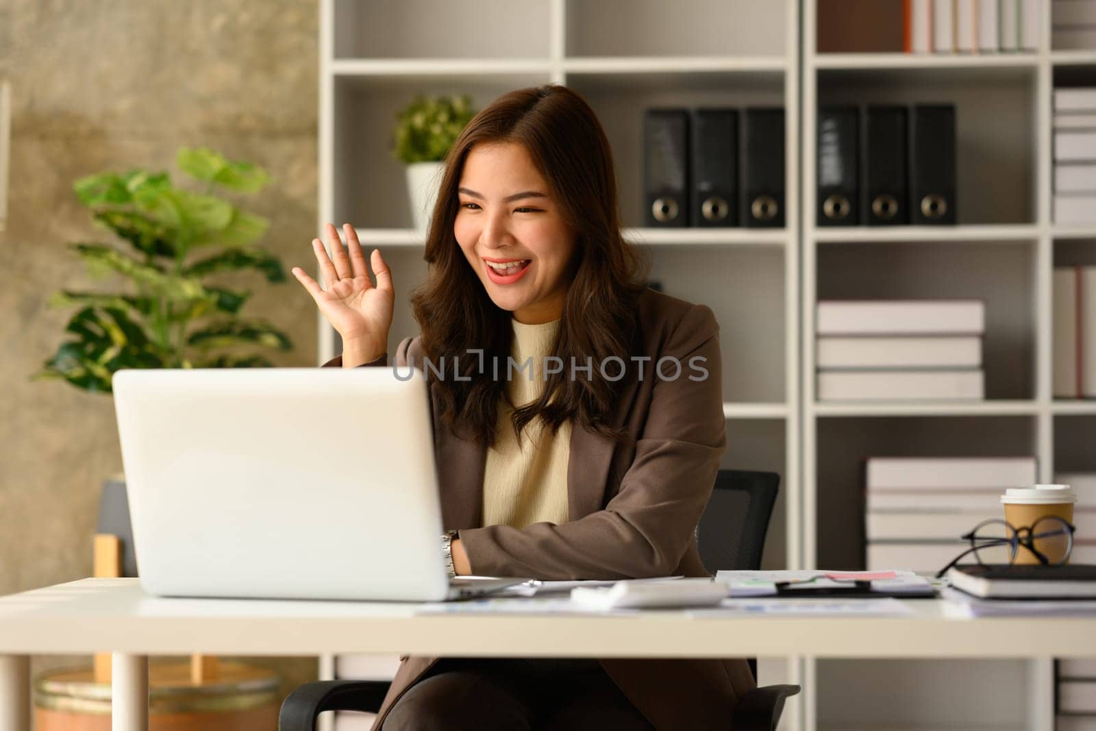 Cheerful female entrepreneur consulting client online, discussing working issues remotely via laptop at workplace.
