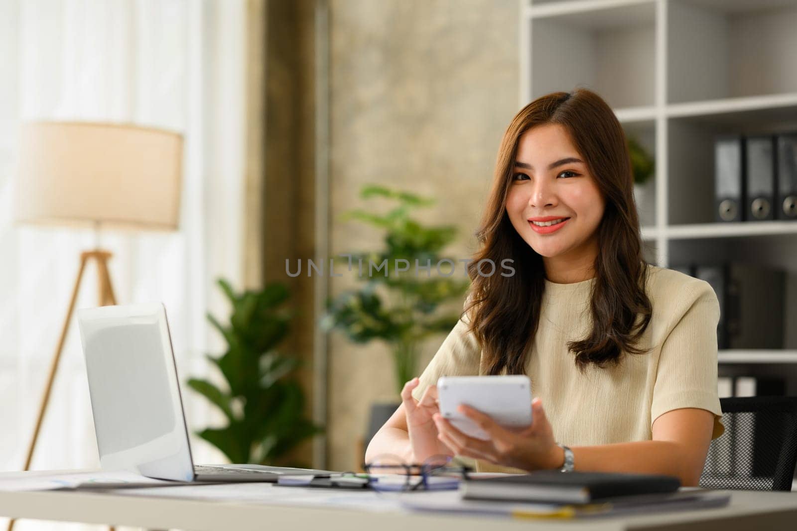 Charming asian female accountant working bookkeeping documents, checking financial data at office.