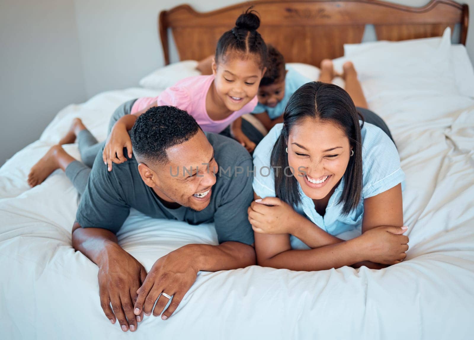 Happy family with kids, smile and lying on bed in home, mother and father with children together in Mexico. Love, fun and family time for dad, mom and babies playing in family bedroom on weekend. by YuriArcurs