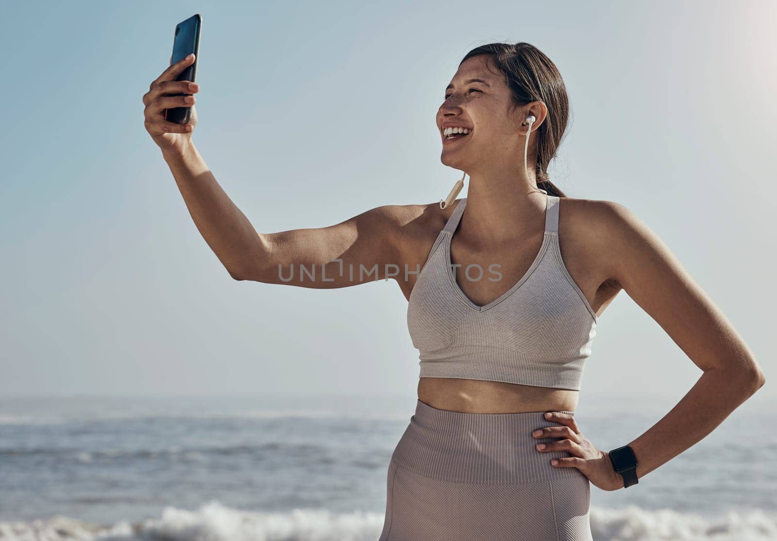 Fitness, selfie and woman at the beach for yoga, training and workout on blue sky background. Social media, live streaming and exercise influencer female recording for blog, post or profile picture.