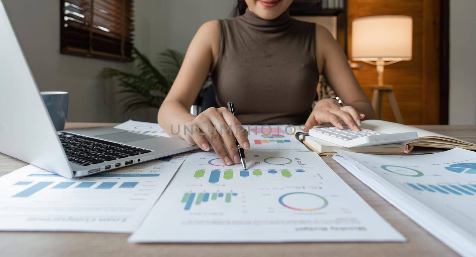 business woman or accountant who are using a calculator to calculate business data Accounting documents and laptop computer at home the business idea.