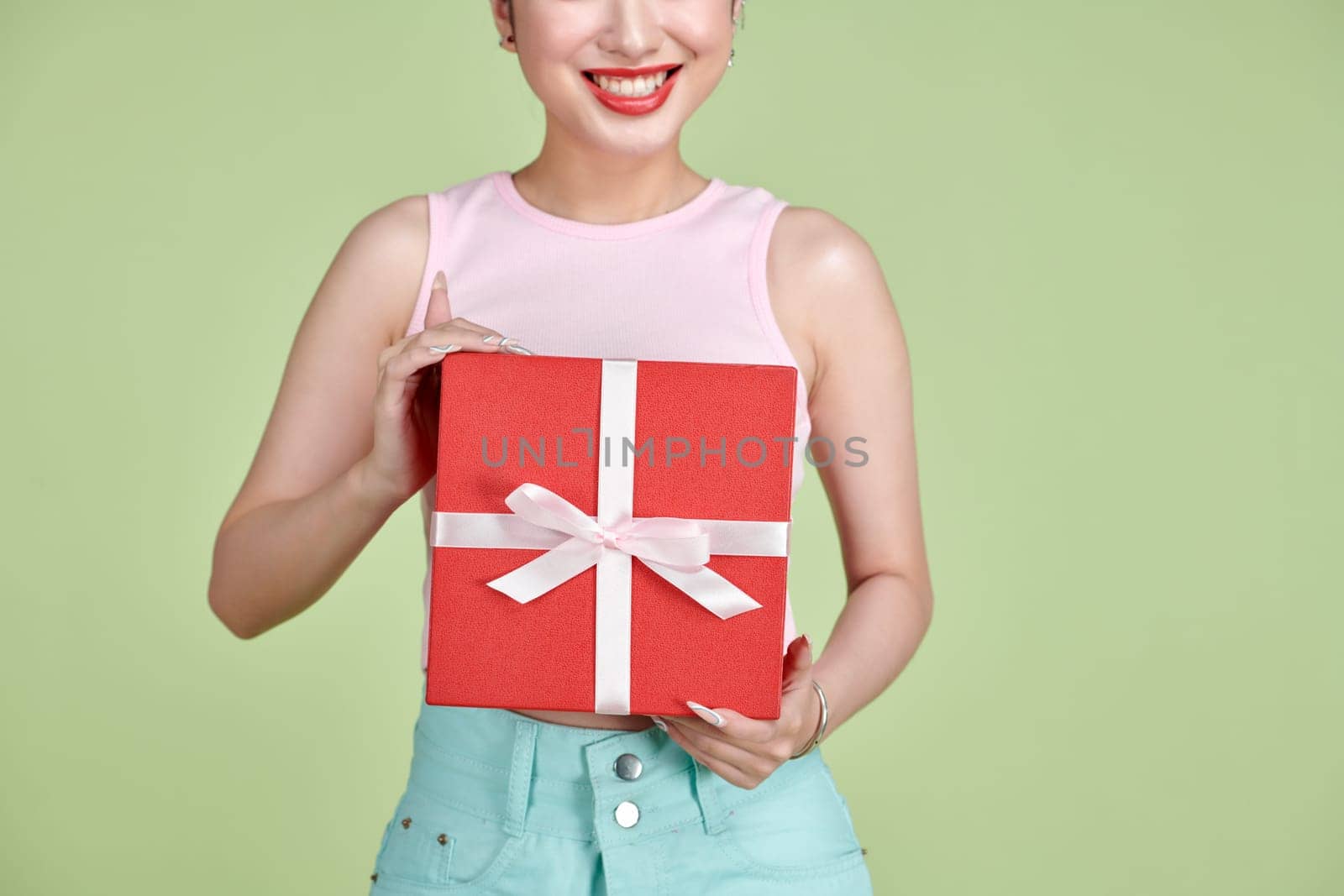 Happy pretty young woman holding gift box over green background by makidotvn