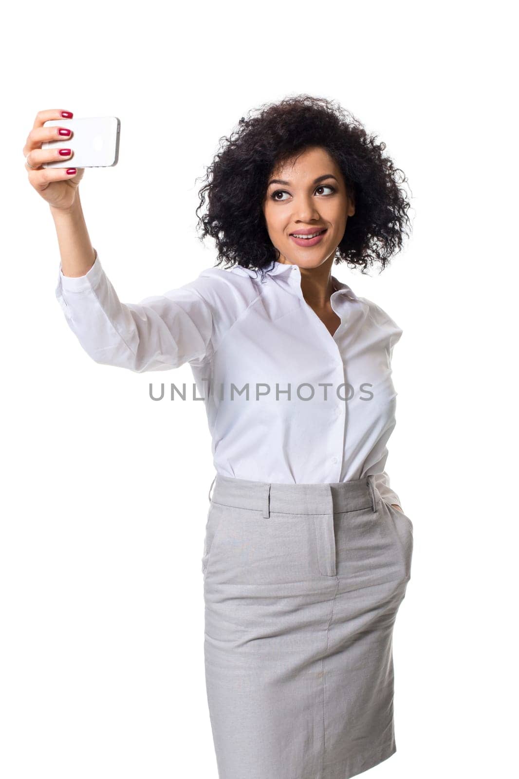 Beautiful brunette woman in classic white shirt and skirt make selfie on the phone. White background. Isolated