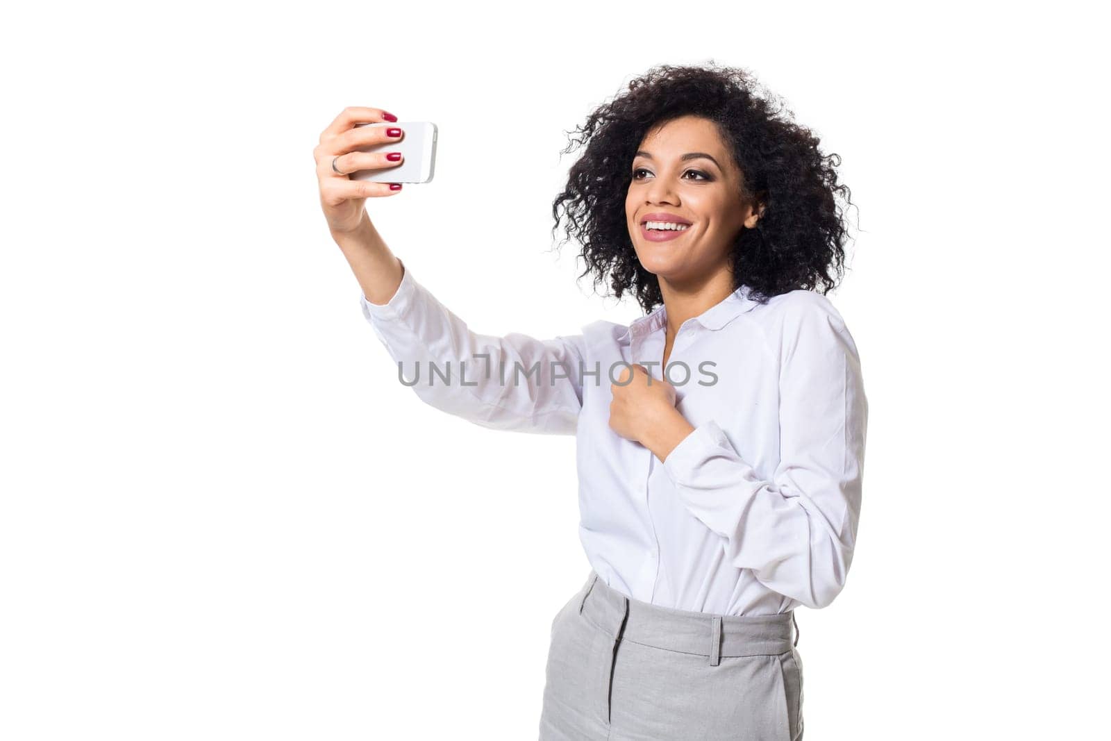 Beautiful brunette woman in classic white shirt and skirt make selfie on the phone. White background. Isolated