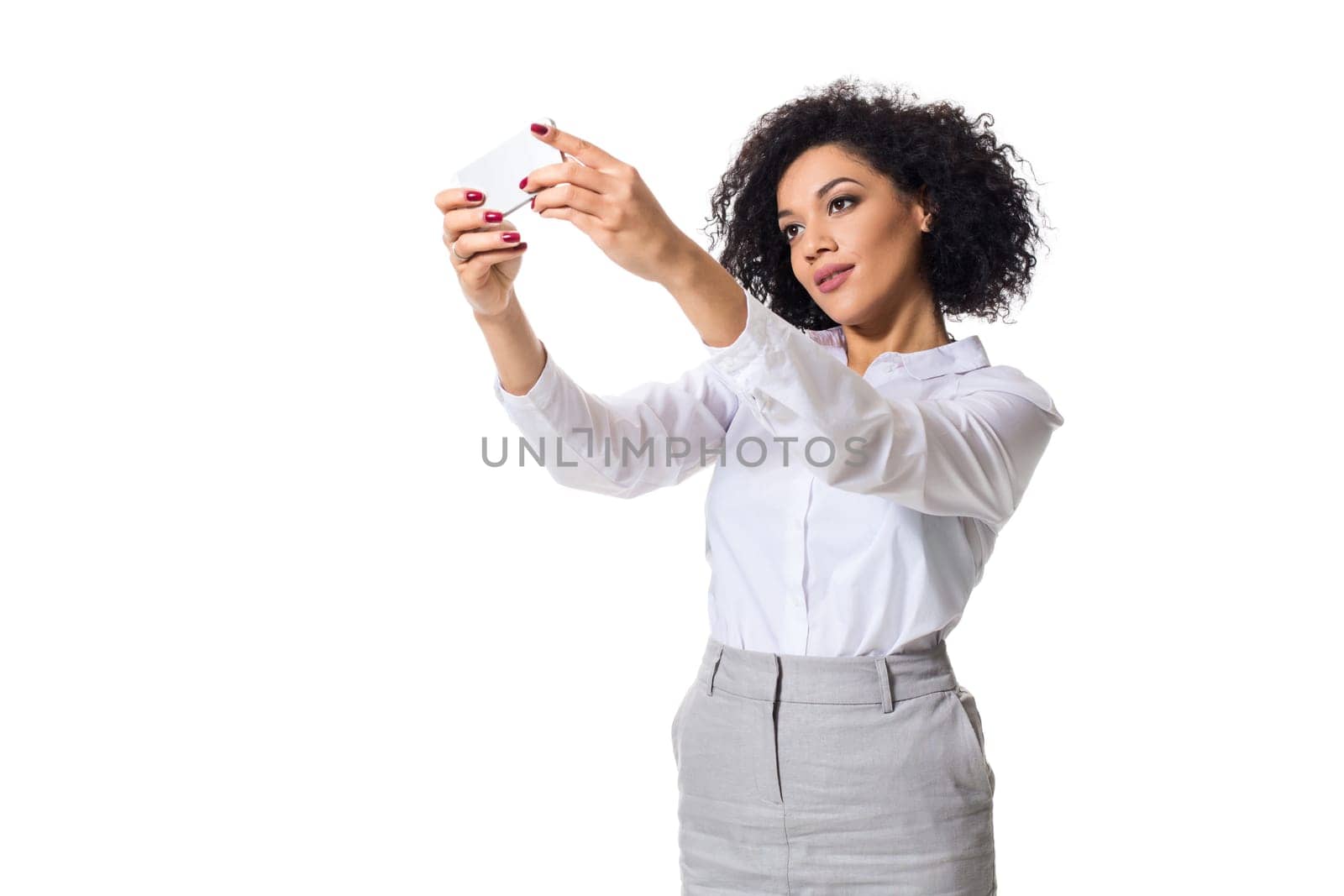Beautiful brunette woman in classic white shirt and skirt make selfie on the phone. White background. Isolated