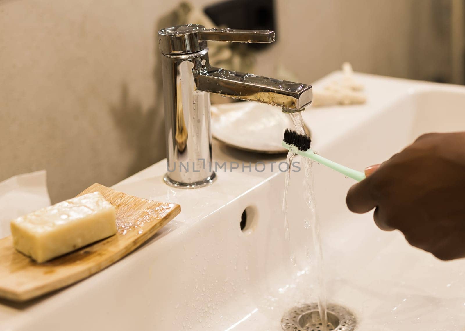 African american male hand holding toothbrush with toothpaste applied on it in bathroom. Close up of man hand ready for brushing teeth. Guy hand holding toothbrush with white tooth paste. by Satura86