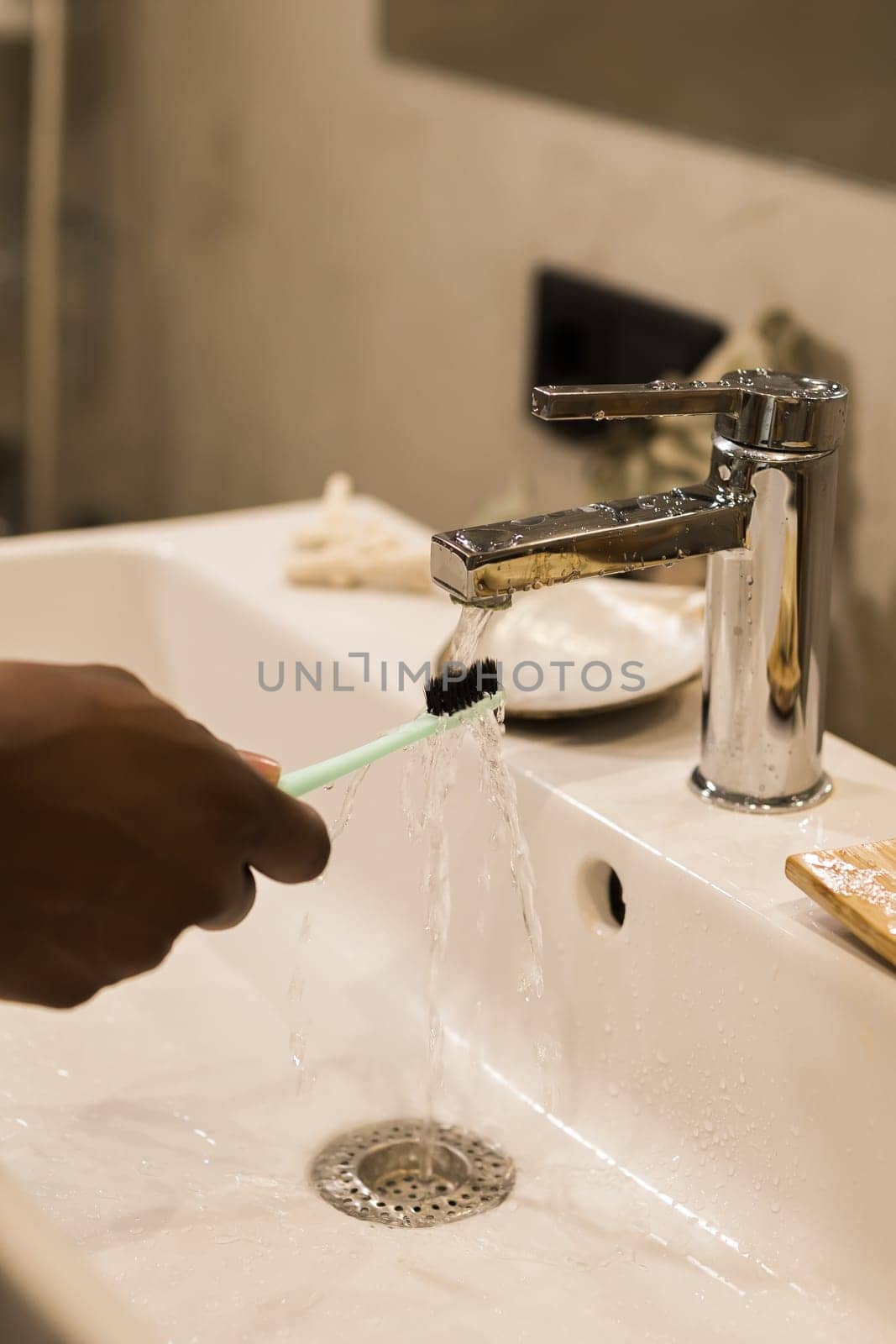 African american male hand holding toothbrush with toothpaste applied on it in bathroom. Close up of man hand ready for brushing teeth. Guy hand holding toothbrush with white tooth paste. by Satura86