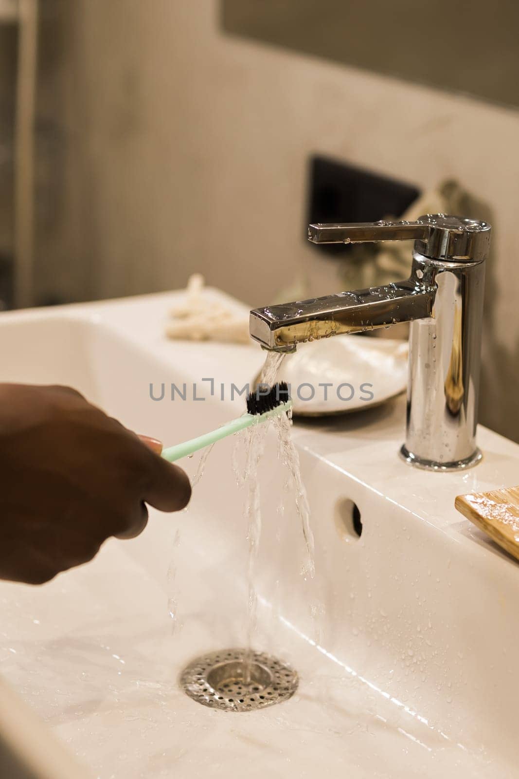 African american male hand holding toothbrush with toothpaste applied on it in bathroom. Close up of man hand ready for brushing teeth. Guy hand holding toothbrush with white tooth paste