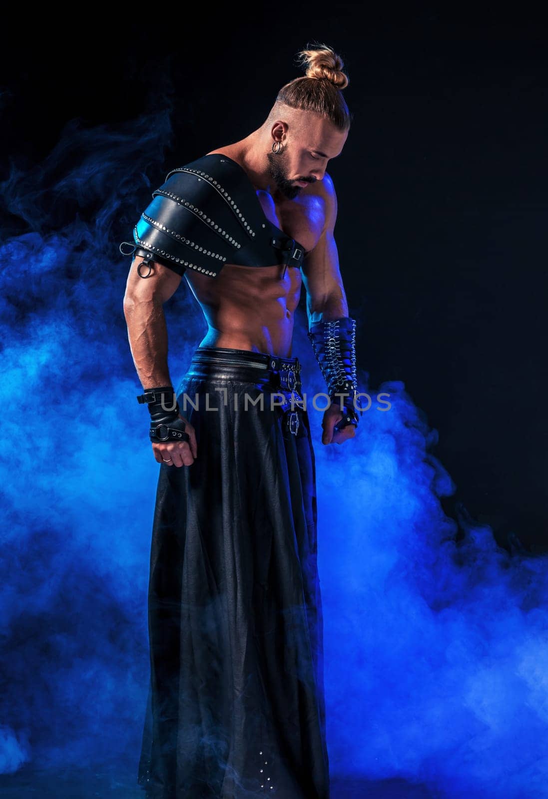 Young and muscular man performing a theatrical pose on a stage. Very sexy man in stage costume