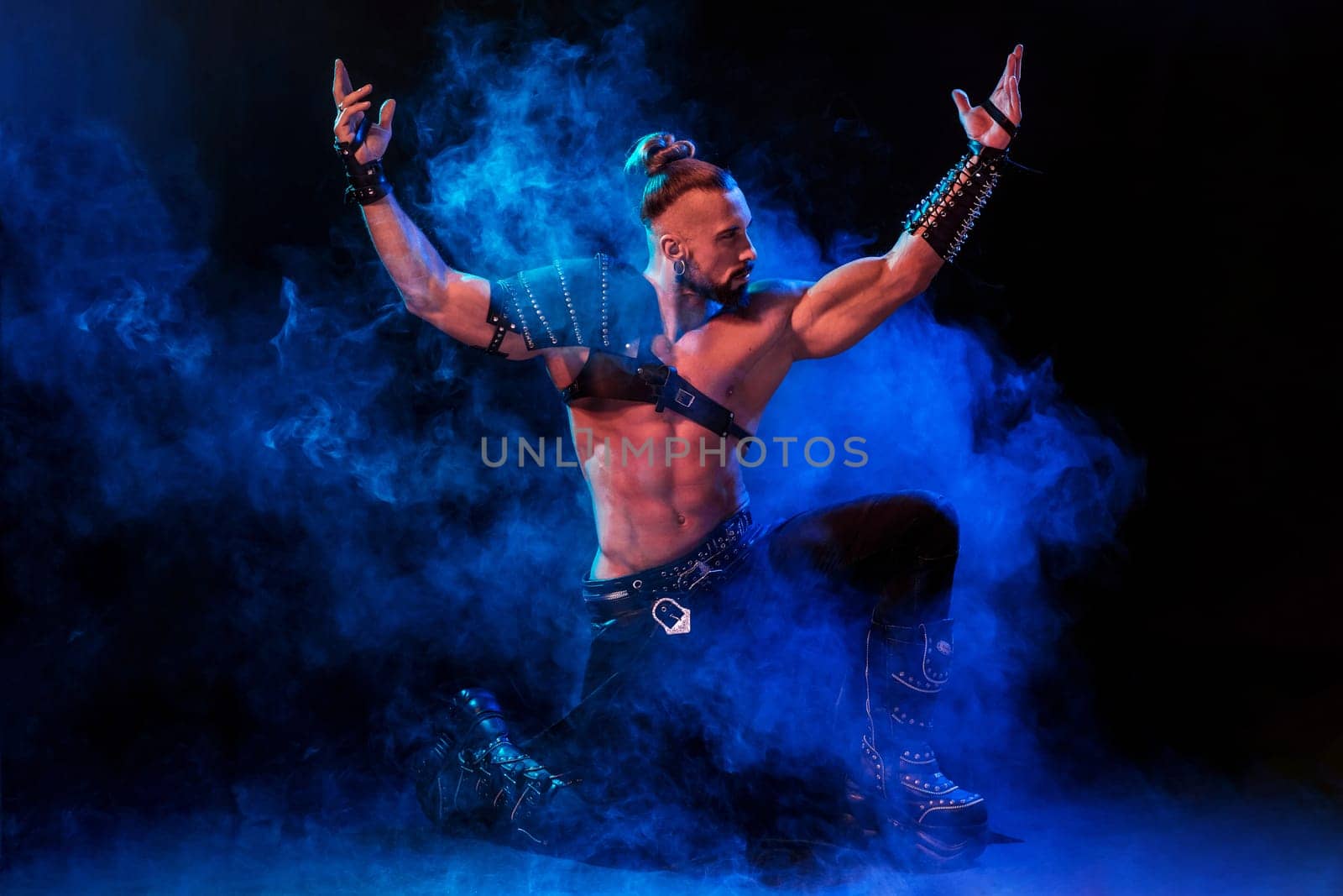 Young and muscular man performing a theatrical pose on a stage. Very sexy man in stage costume