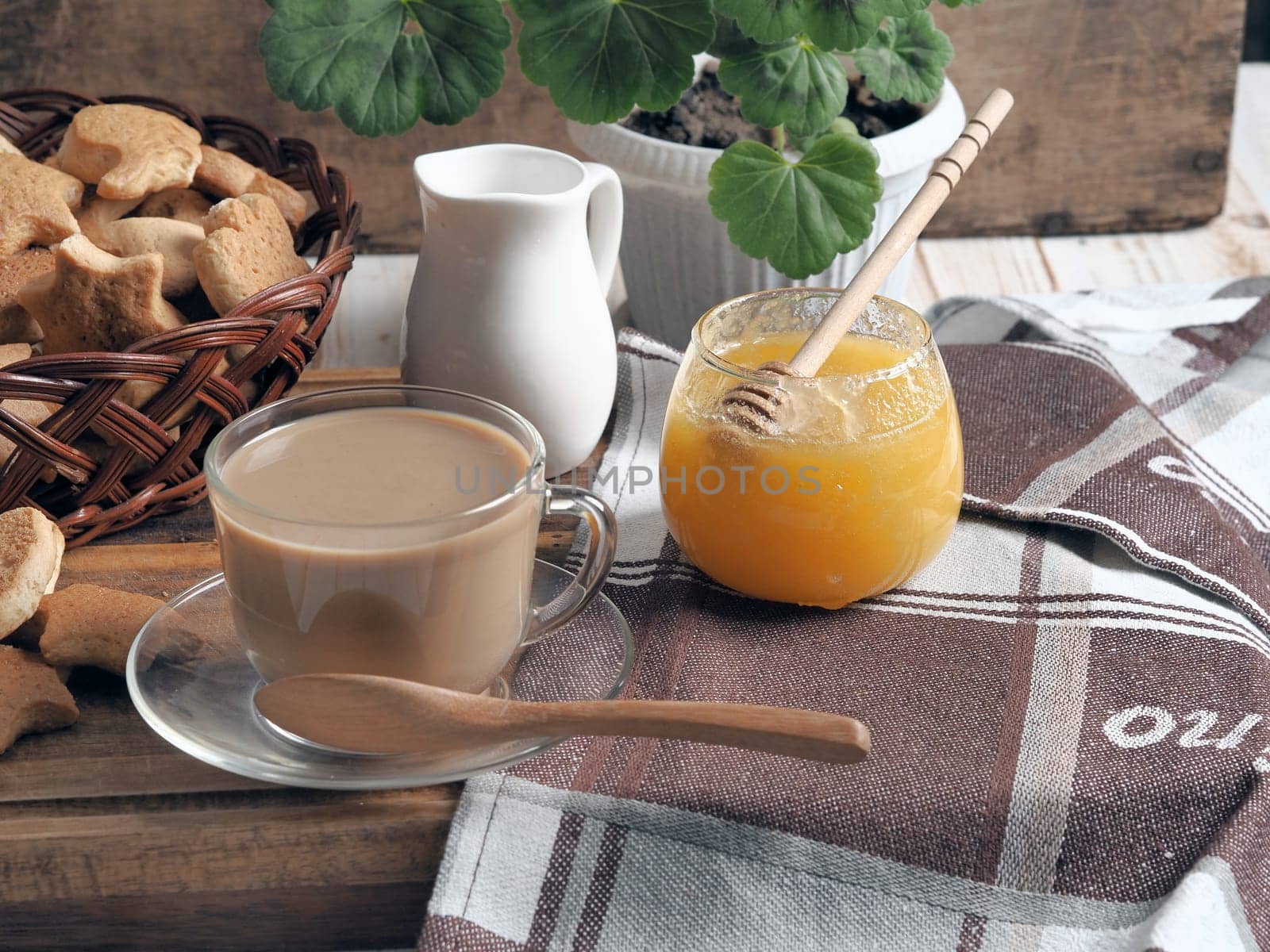 Food background.Healthy homemade food.A cup of tea with milk and homemade butter cookies. Still life on a brown background of a rustic kitchen table with scattered biscuits and honey.