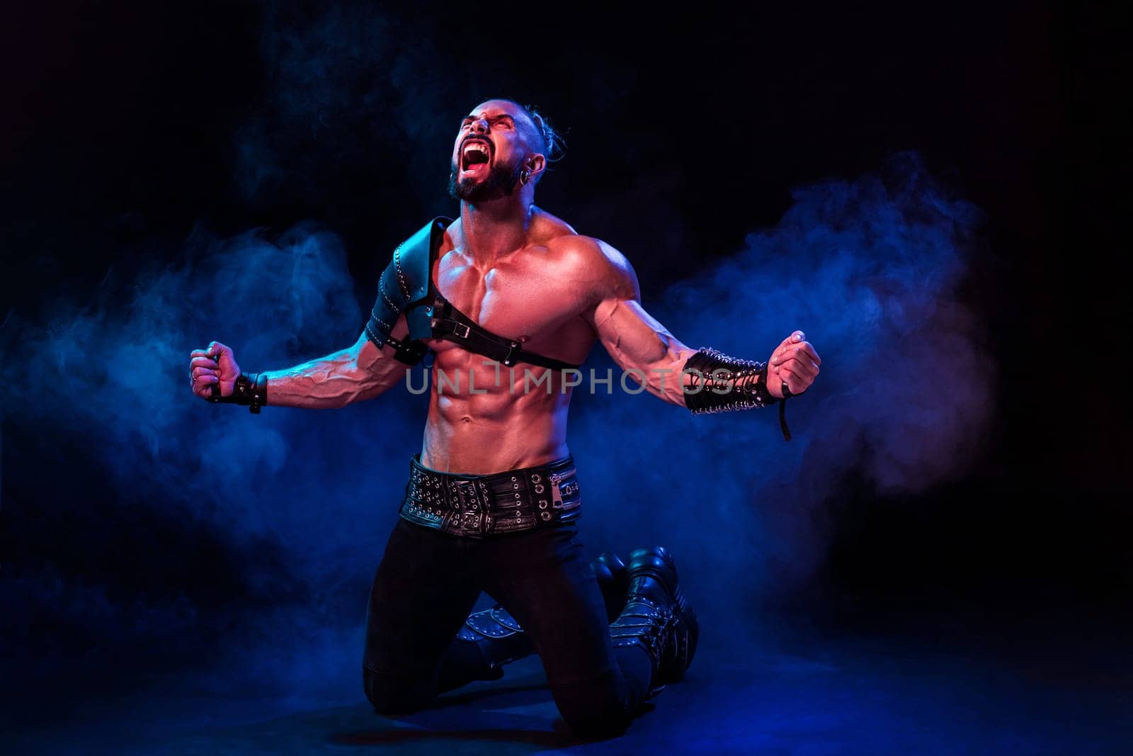 Young and muscular man performing a theatrical pose on a stage. Very sexy man in stage costume
