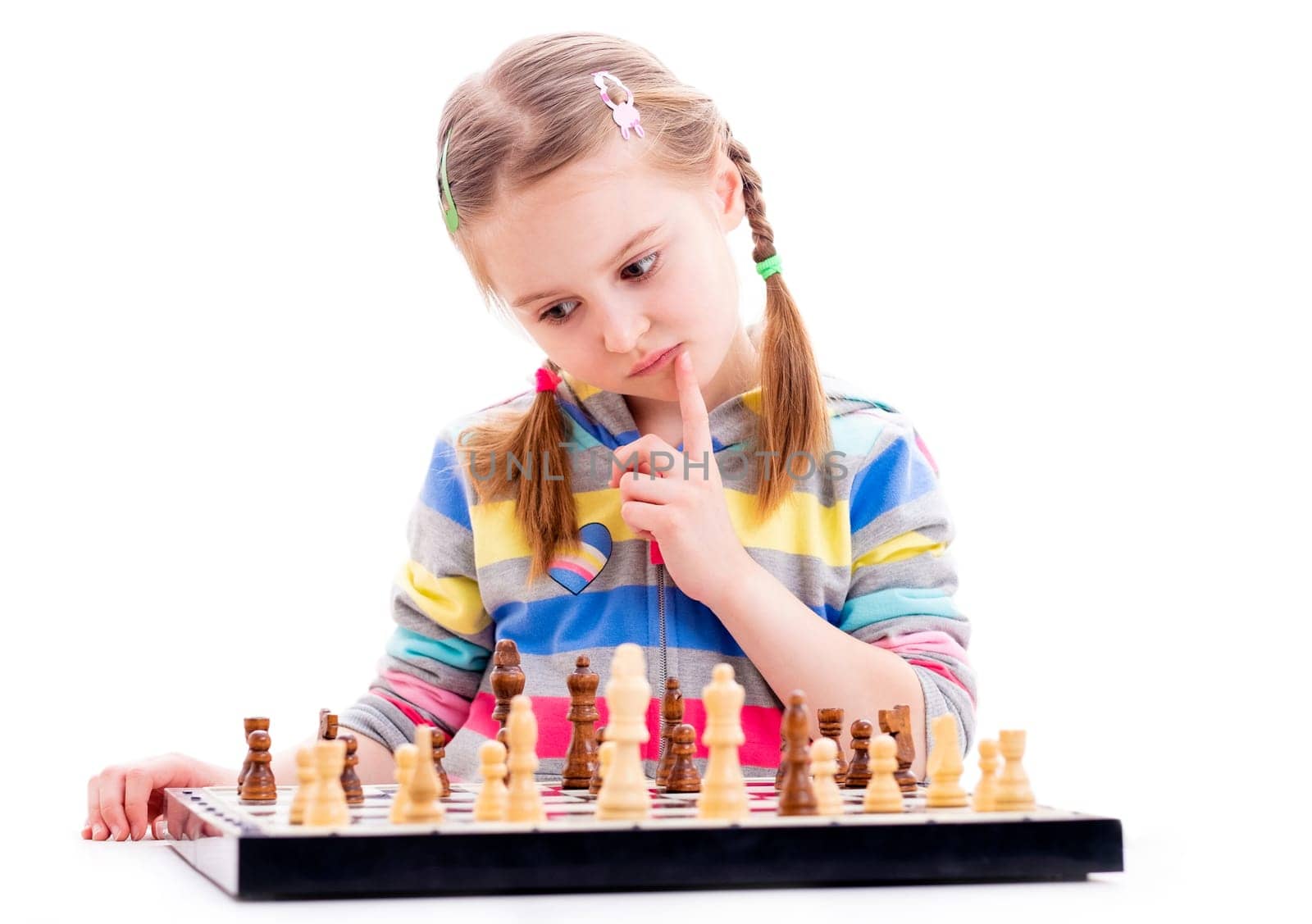 Cute small girl is hardly concentrated, when plating chess game isolated on a white background