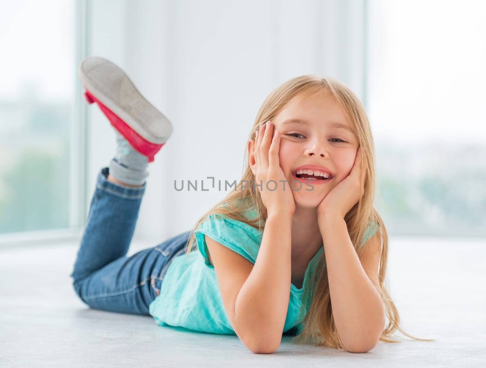 Cheerful little girl lying head on hands