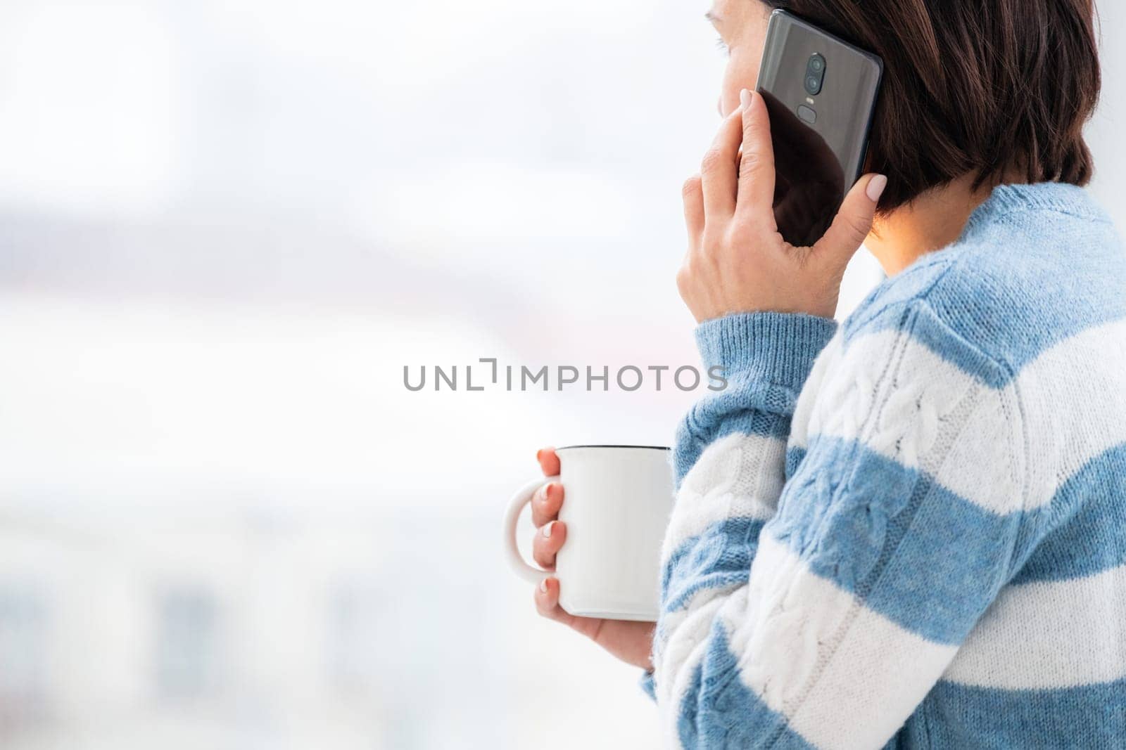 Girl talking on phone while drinking from cup