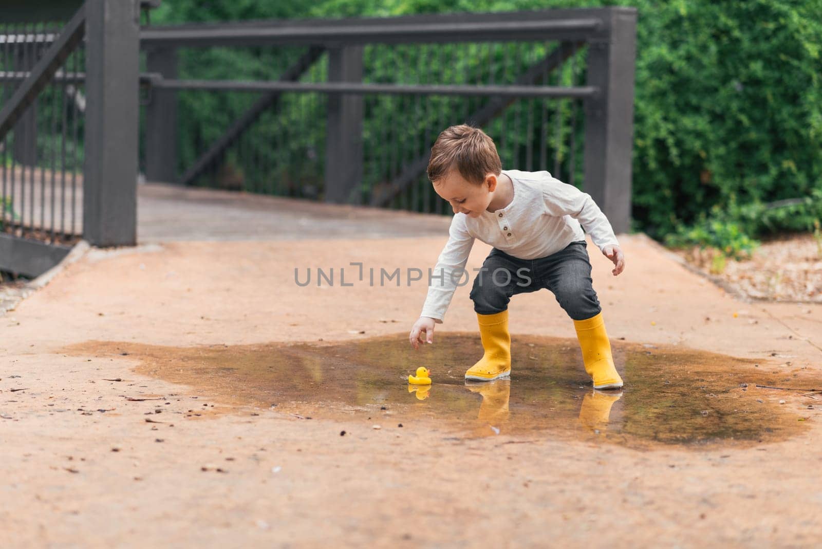 happy child with yellow rubber duck in a puddle in autumn in nature.