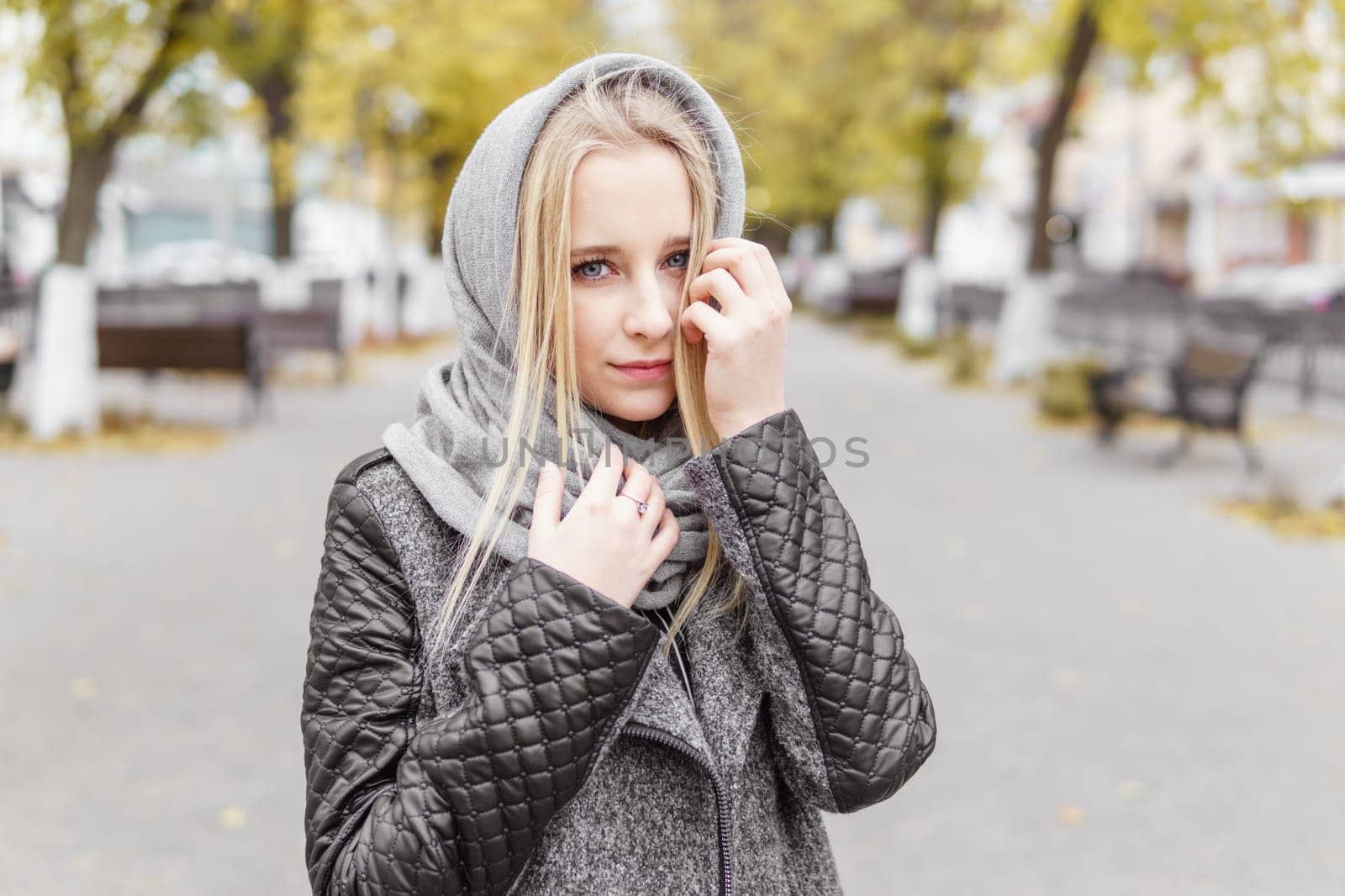 A young blonde walks through the autumn city in a gray coat. The concept of urban style and lifestyle. by Annu1tochka