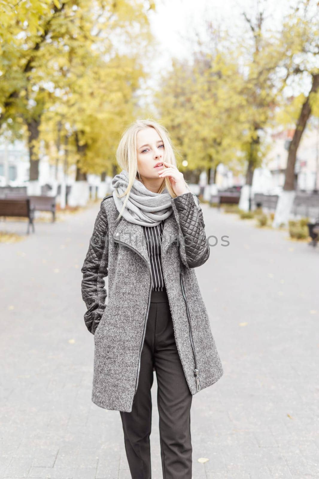 A young blonde walks through the autumn city in a gray coat. The concept of urban style and lifestyle. by Annu1tochka