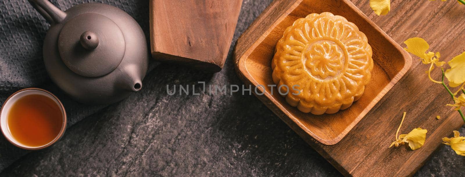 Mid-Autumn Festival traditional food concept - Beautiful Moon cake on black slate table with tea, pastry mold, flower, top view, flat lay, copy space