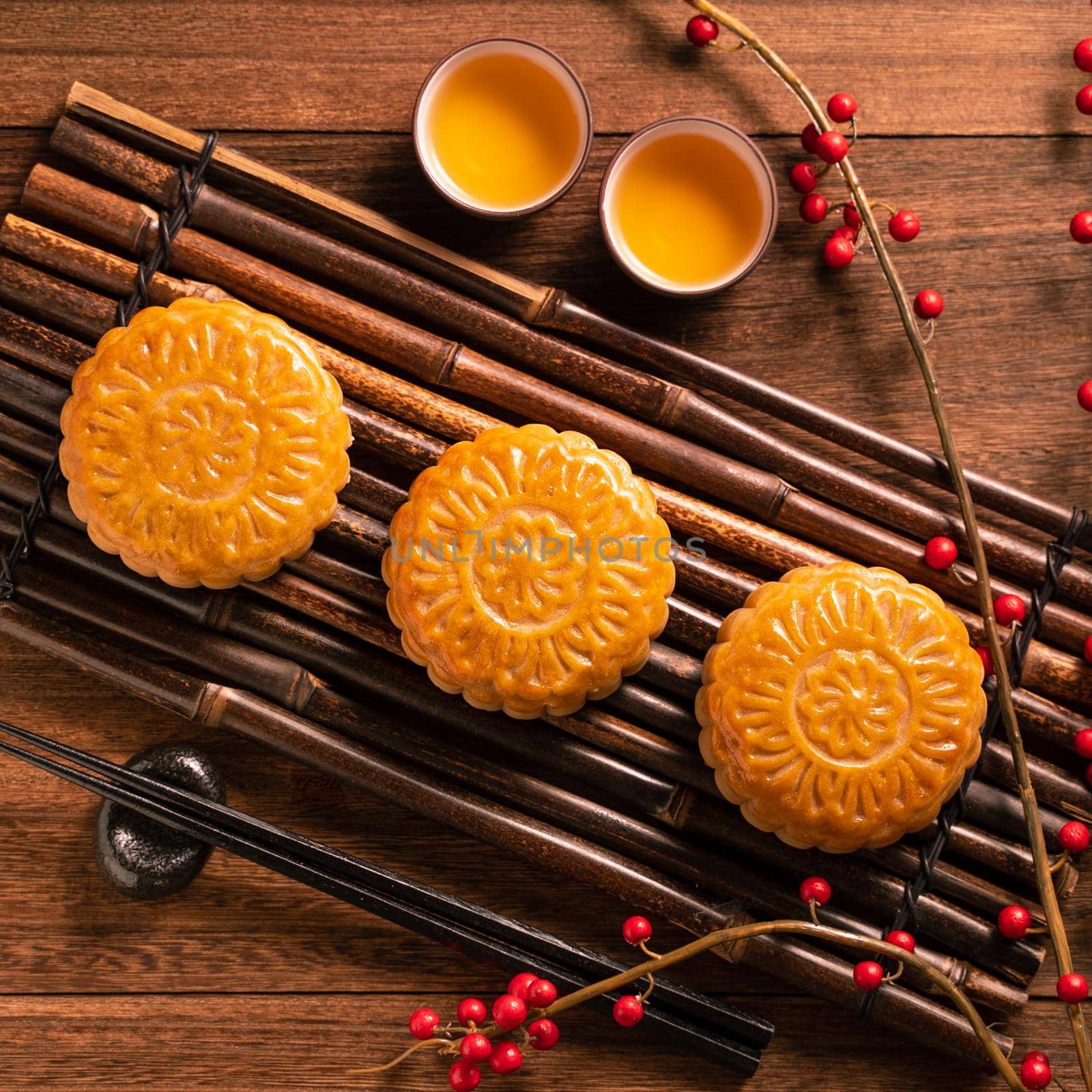 Chinese traditional pastry Moon cake Mooncake with tea cups on bamboo serving tray on wooden background for Mid-Autumn Festival, top view, flat lay. by ROMIXIMAGE