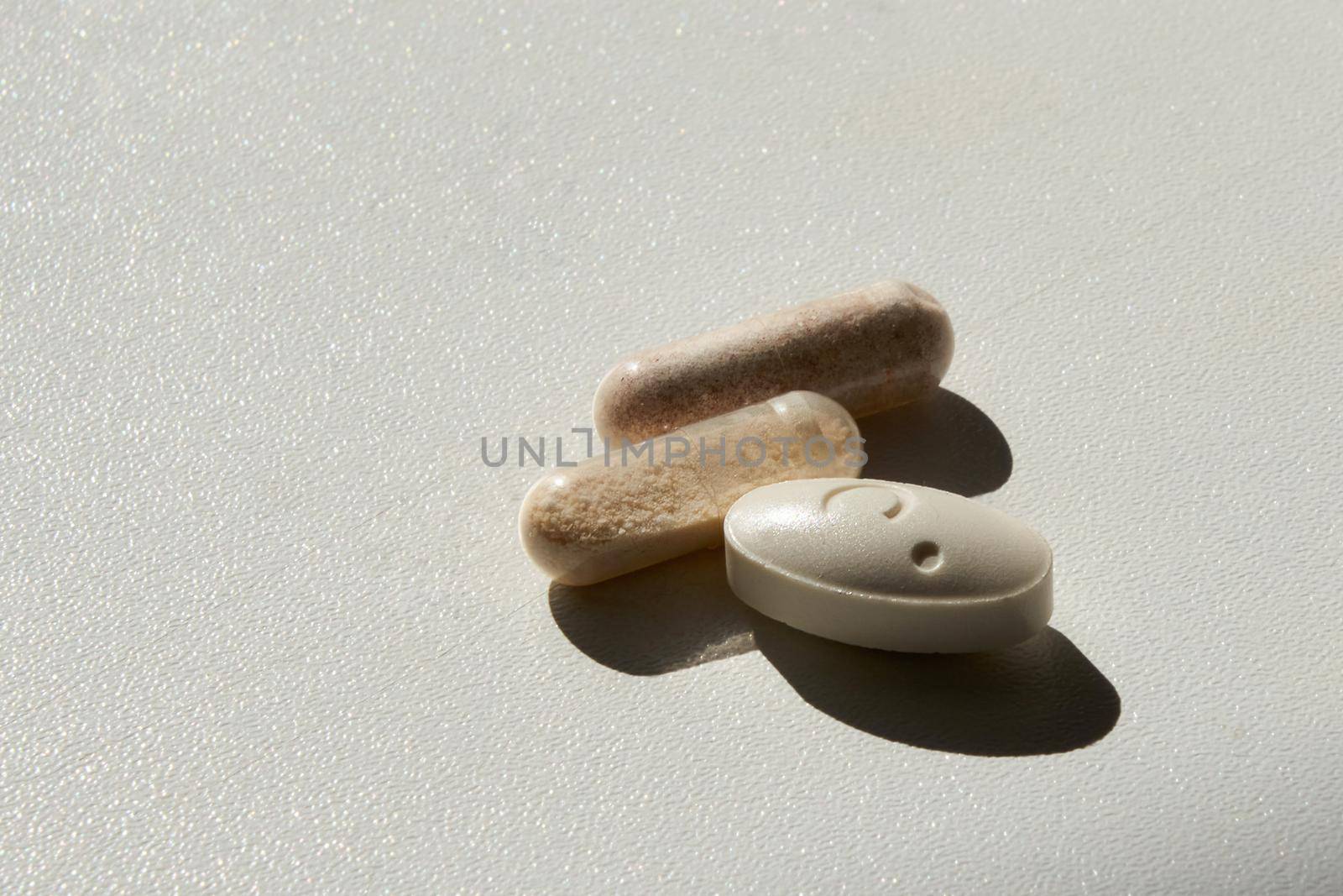 three pills on white table with hard shadows, medicine concept