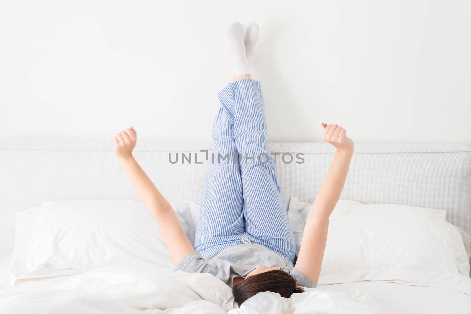 Girl with legs up lying on bed in bedroom by Mariakray