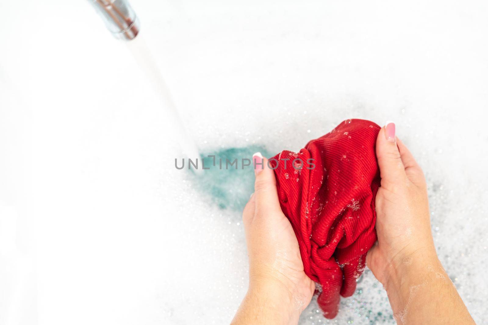 Female hands washing color clothes in basin