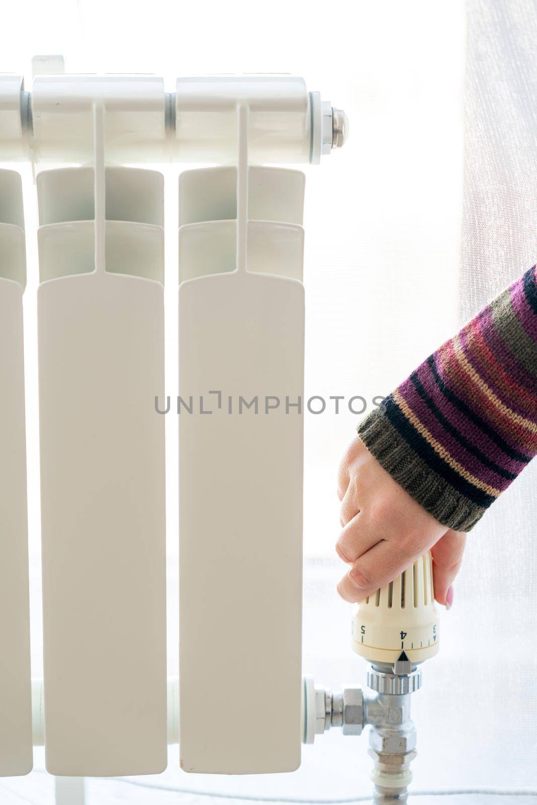 Radiator adjustment closeup. Female hand adjusting radiator temperature by Mariakray