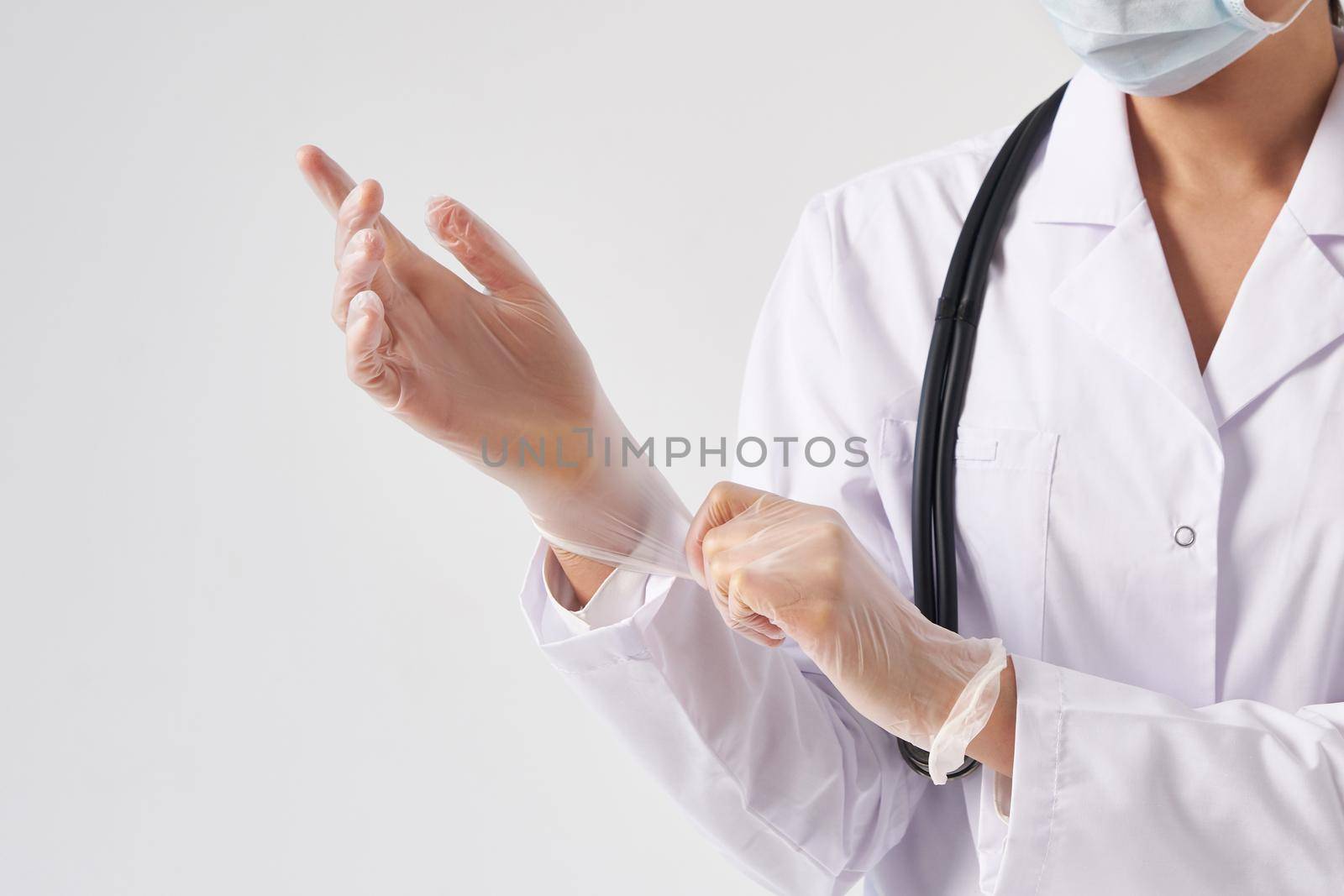 Young doctor putting on surgical gloves over white background by Mariakray