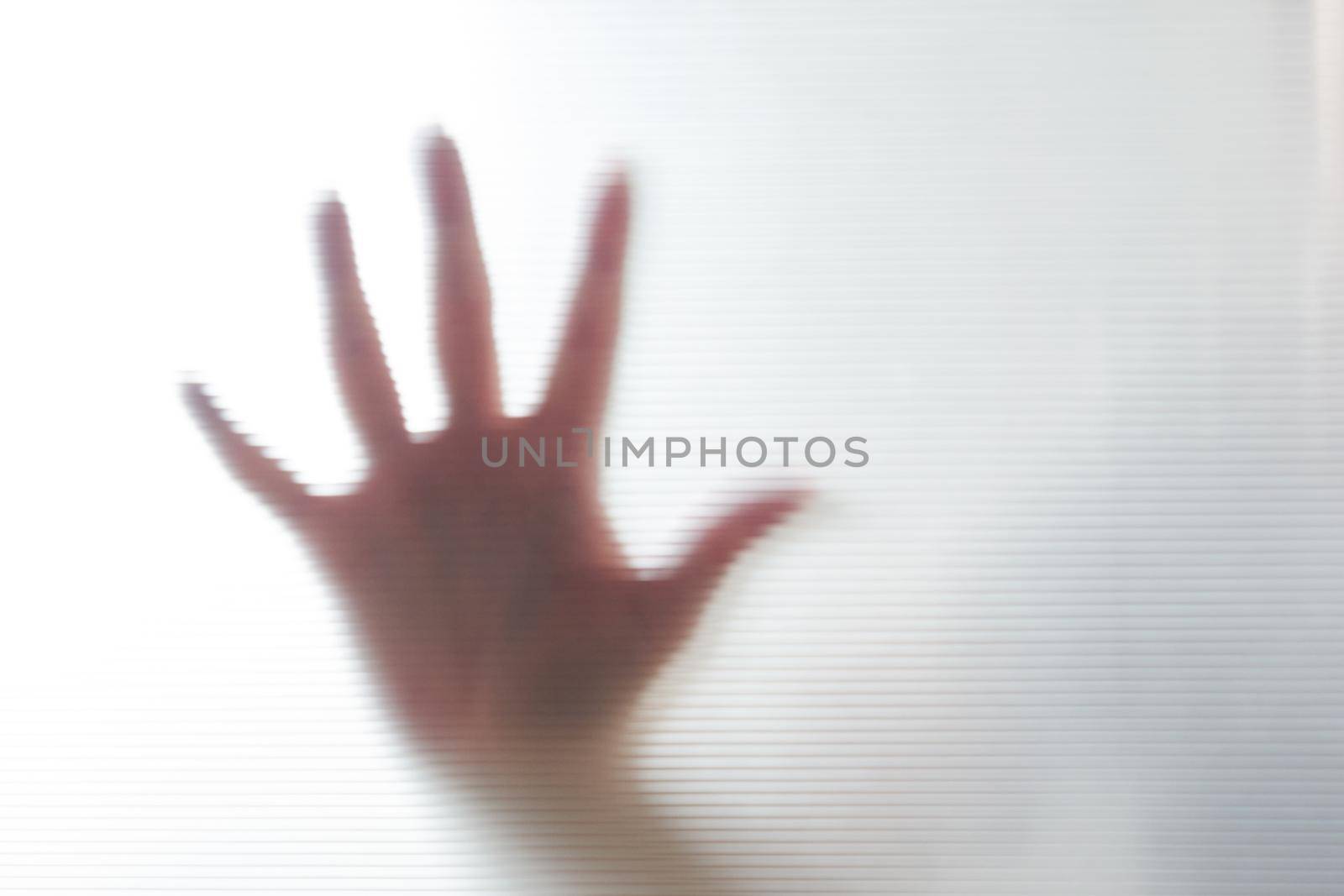 Diffused silhouette of female hands through frosted glass