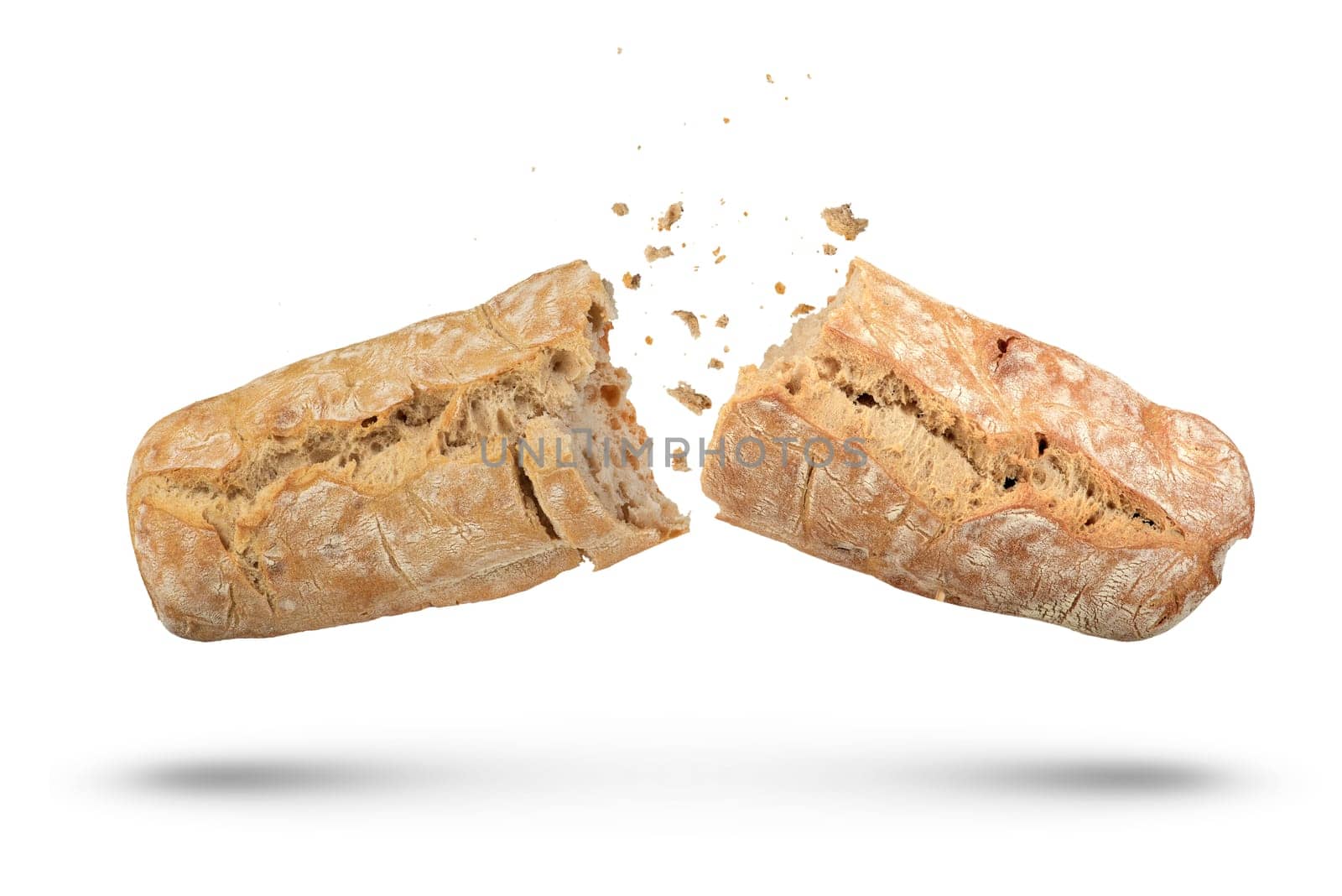 A loaf of Italian fresh ciabatta bread is broken into 2 parts on a white isolated background. Ciabatta bread isolate on a white background, bread crumbs scatter in different directions. side view