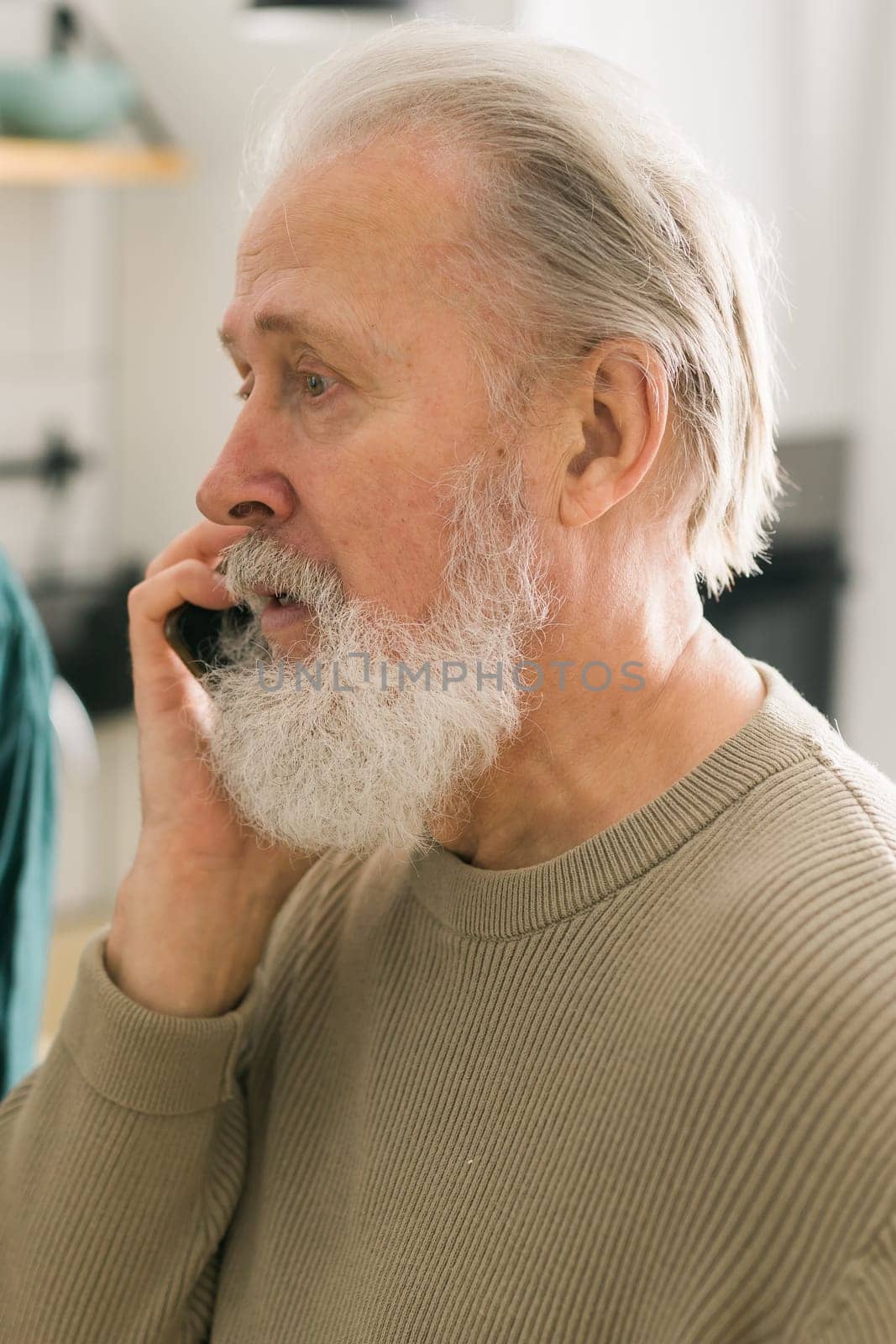 Happy bearded aged senior man talking by phone at home - active senior aged and communication