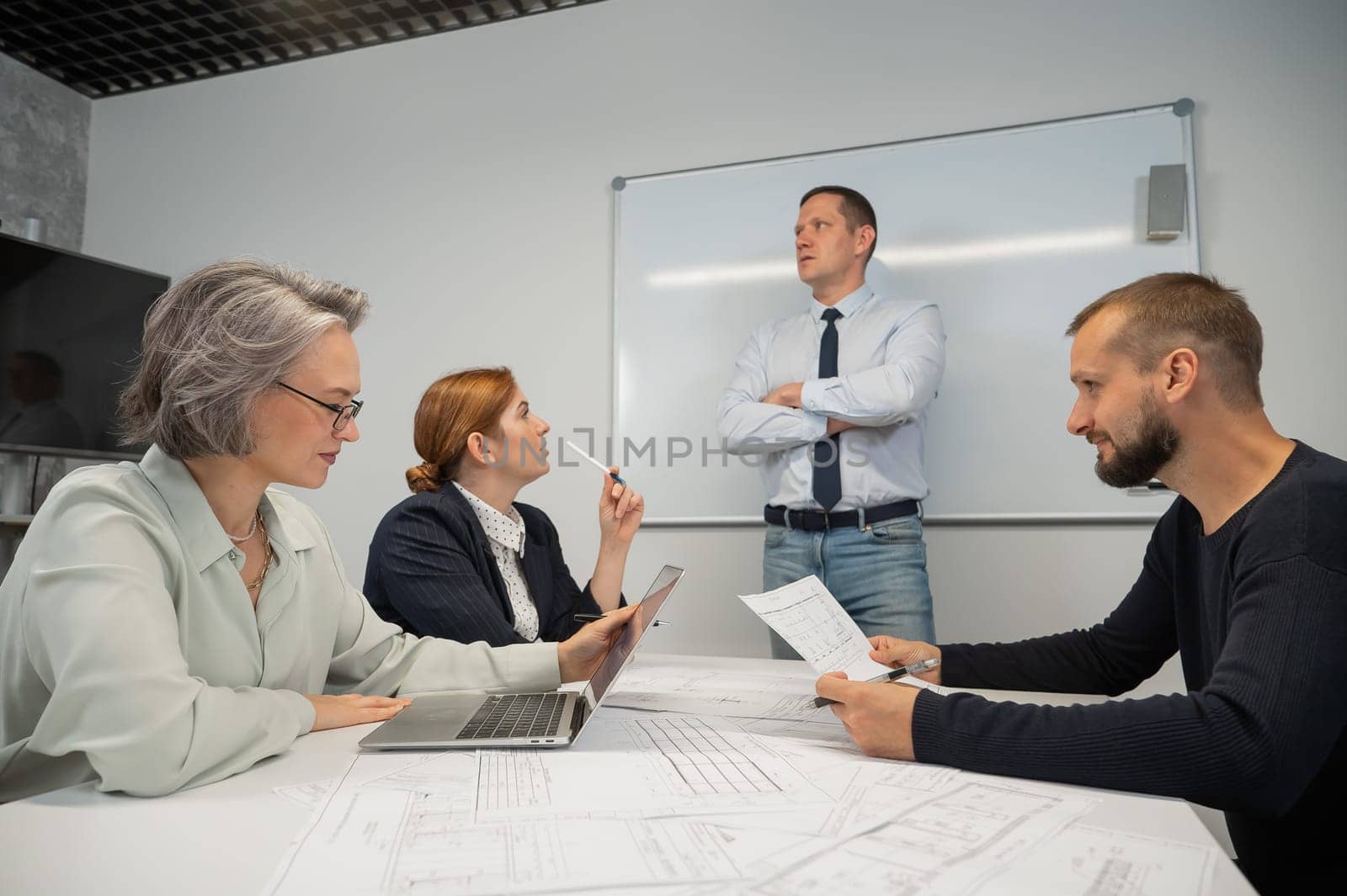 Caucasian man leading a presentation to colleagues at a white board