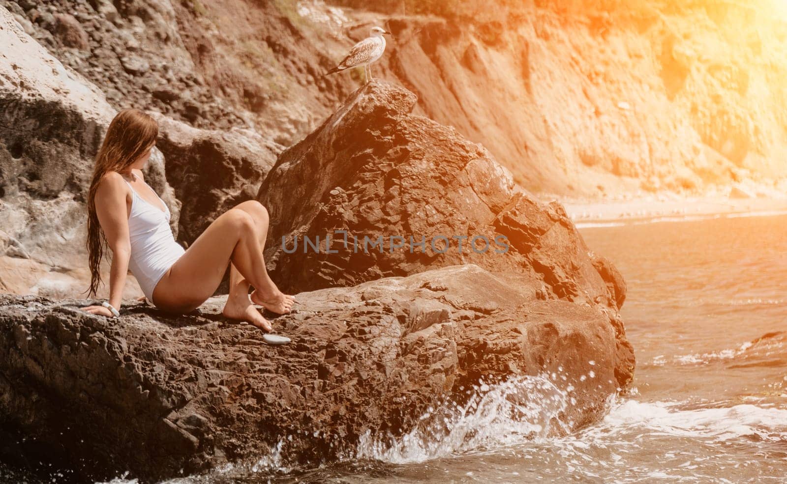 Woman travel sea. Young Happy woman in a long red dress posing on a beach near the sea on background of volcanic rocks, like in Iceland, sharing travel adventure journey