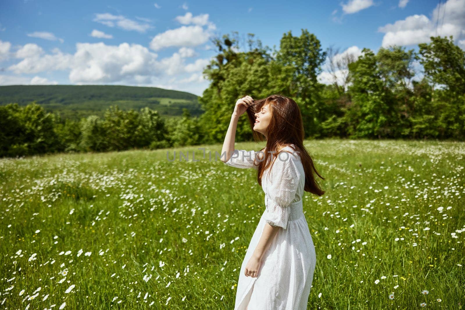 portrait of a woman in a light dress in a chamomile field turning her face away from the camera. High quality photo