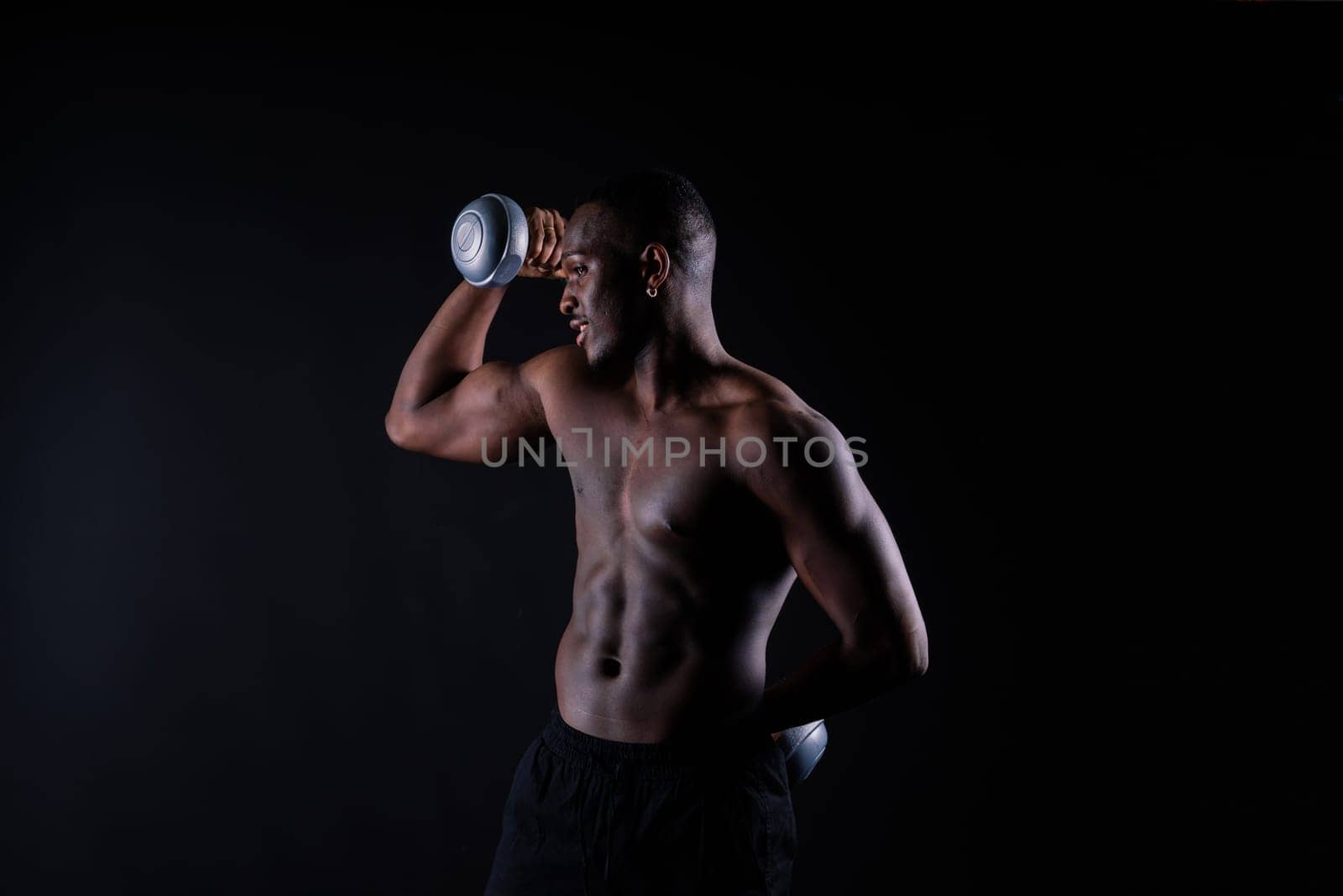 Portrait of a happy african man with dumbbells over red and black background by Zelenin