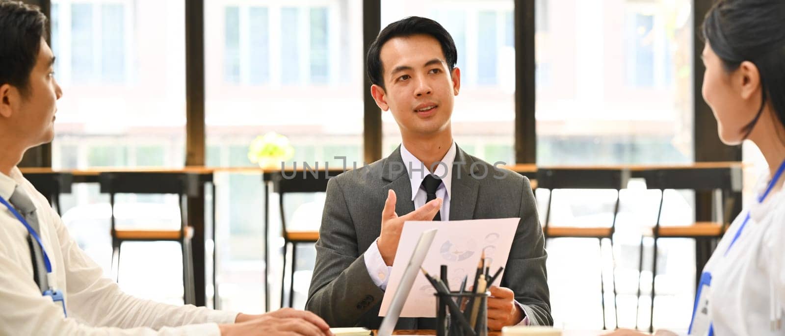 Confidence male broker talking, consulting, giving instructions, explaining terms of contract to business partners at meeting.