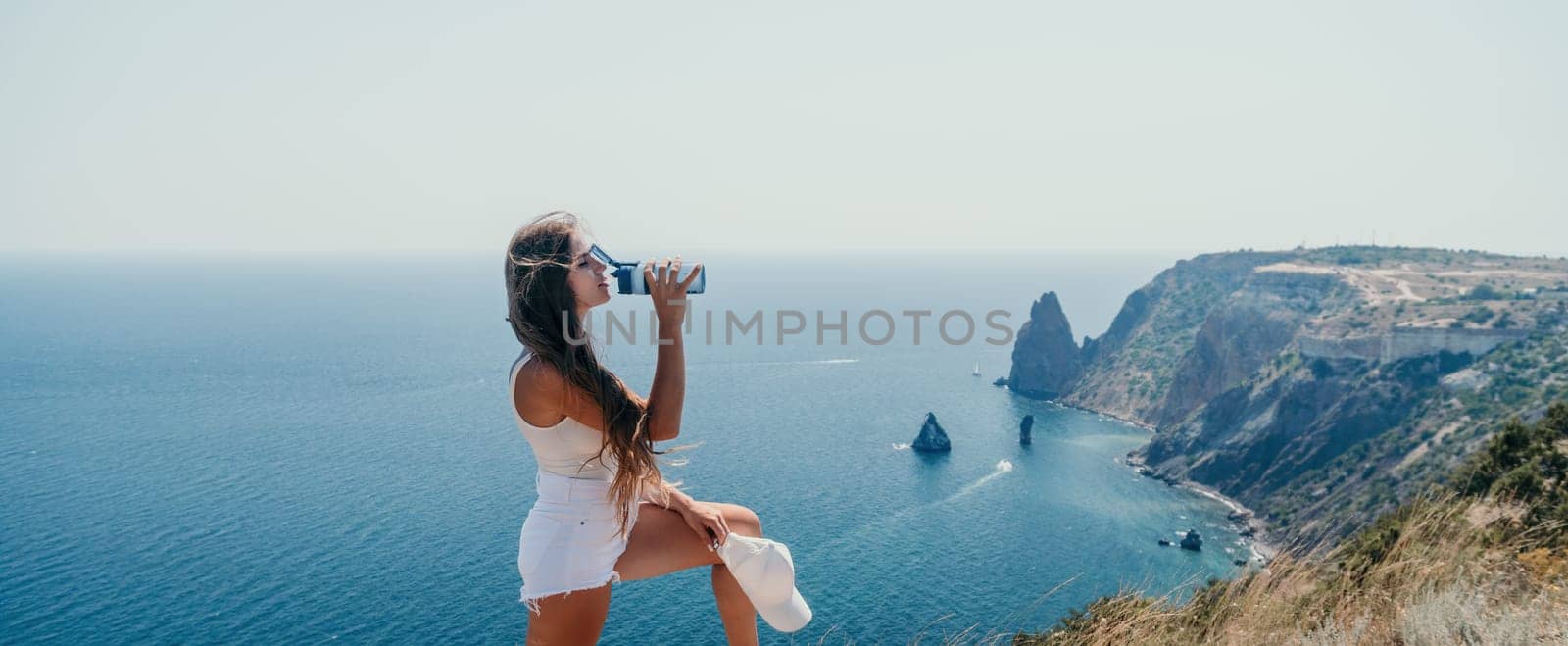 Woman summer travel sea. Happy tourist enjoy taking picture outdoors for memories. Woman traveler posing over sea bay surrounded by volcanic mountains, sharing travel adventure journey by panophotograph