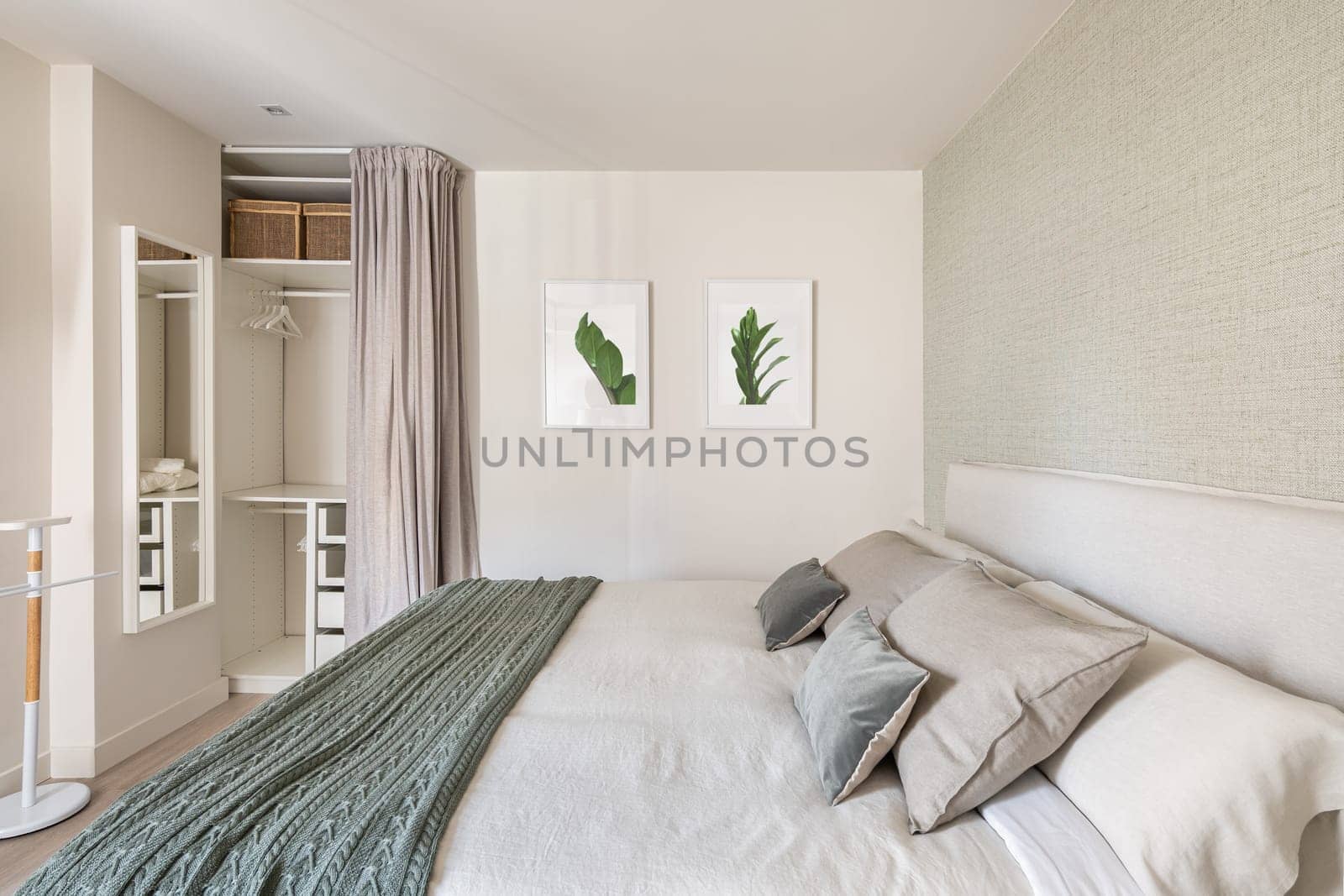 Comfortable bright bedroom with double bed and an empty wardrobe for clothes with beige wallpaper and cute pictures on the wall. The concept of moving to a new apartment.