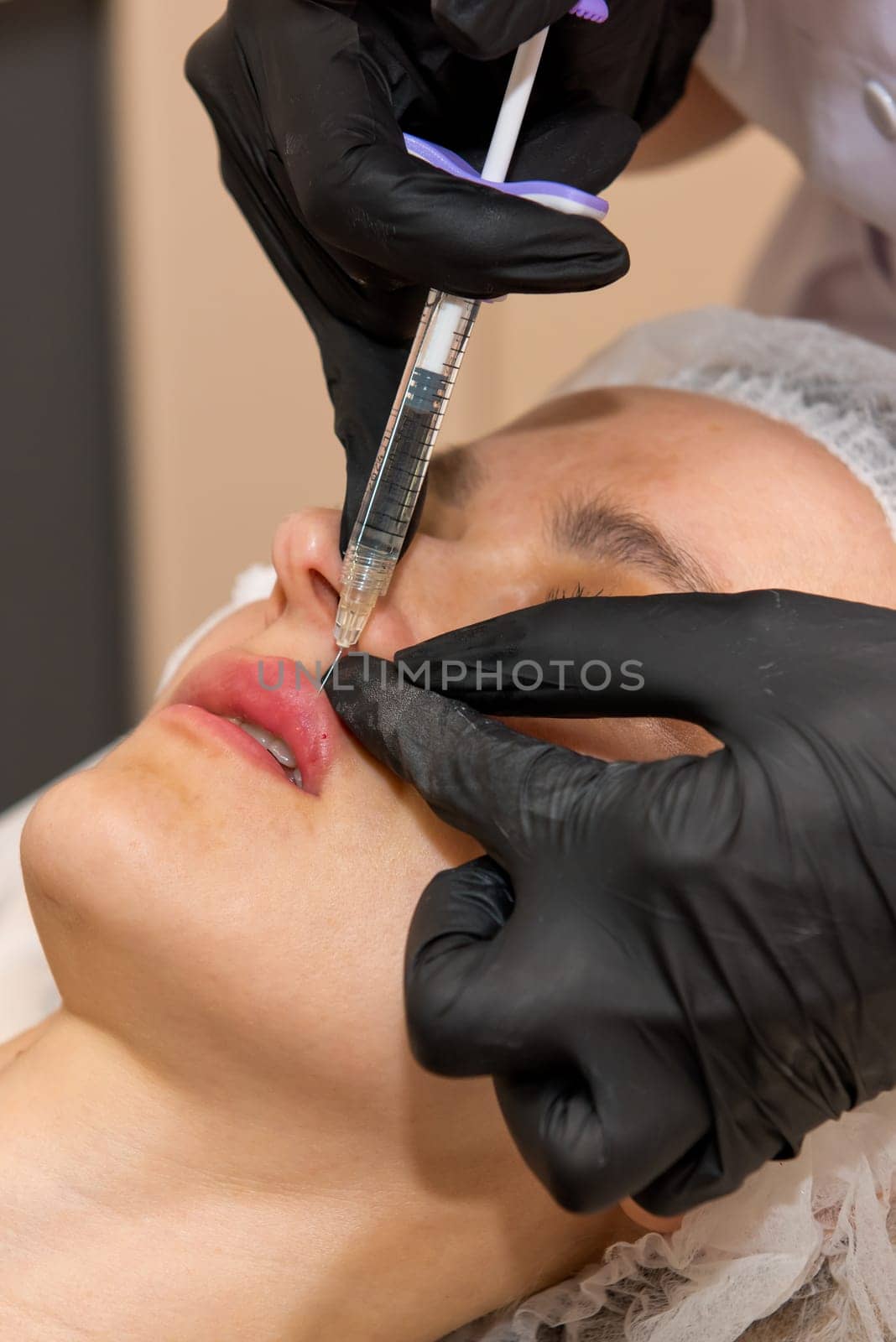 Beauty injections. Young woman receiving a injection in her lips. Selective focus. by leonik