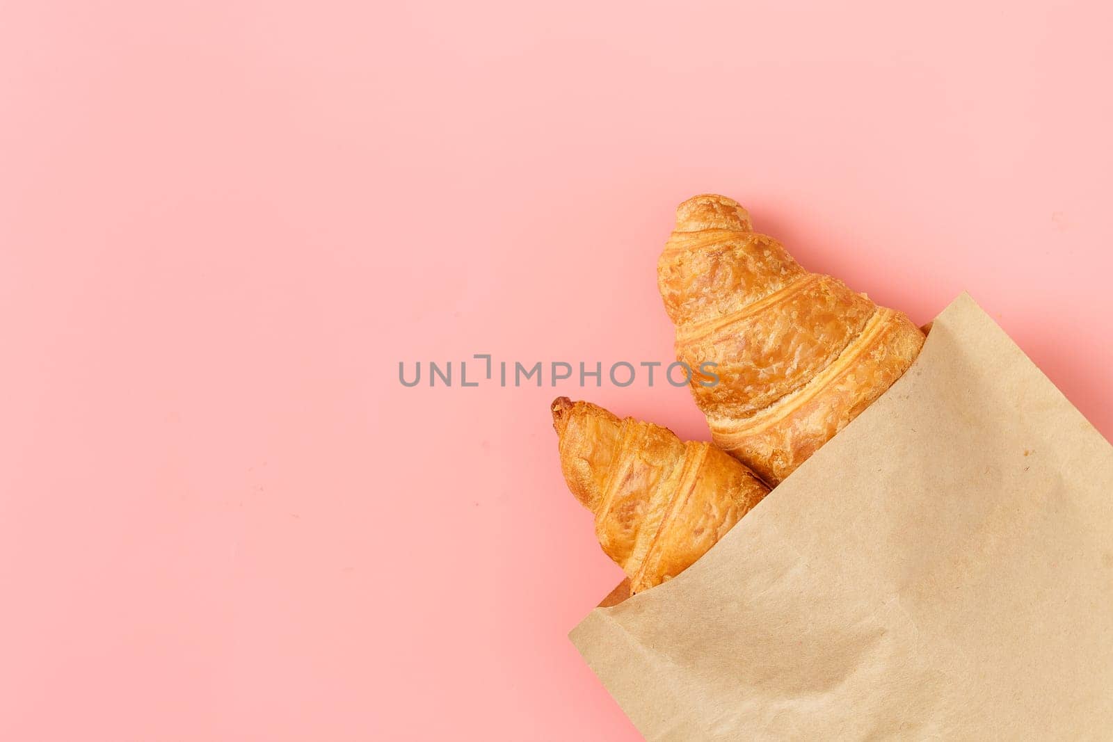 Delicious croissants in a package on a pink background. french pastries. copy space.