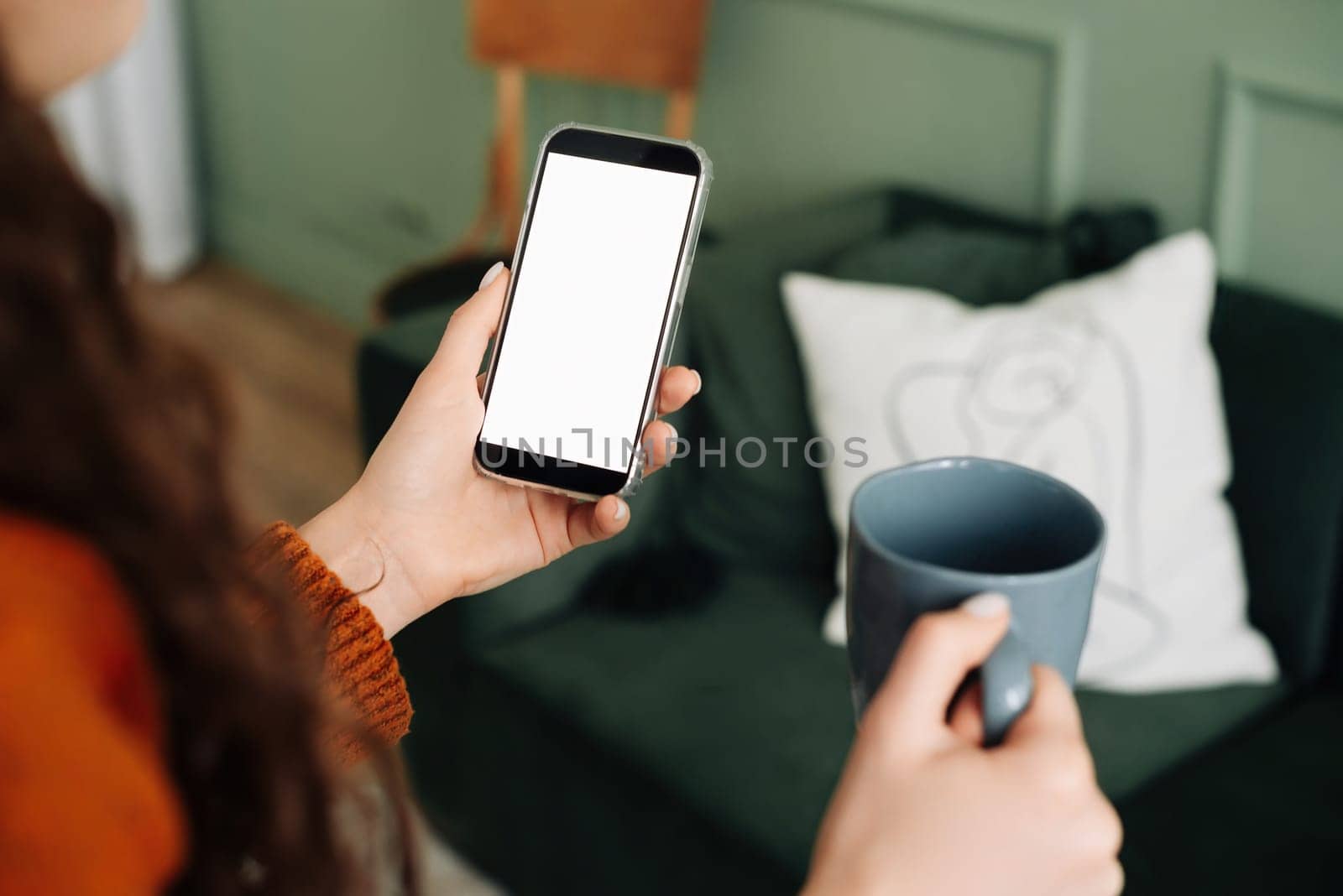 Mockup Smartphone Display: Woman Holding Coffee and Texting on Cellphone Apps, Over Shoulder View for Advertising and Promotions. smartphone with a blank screen for mobile application layout.
