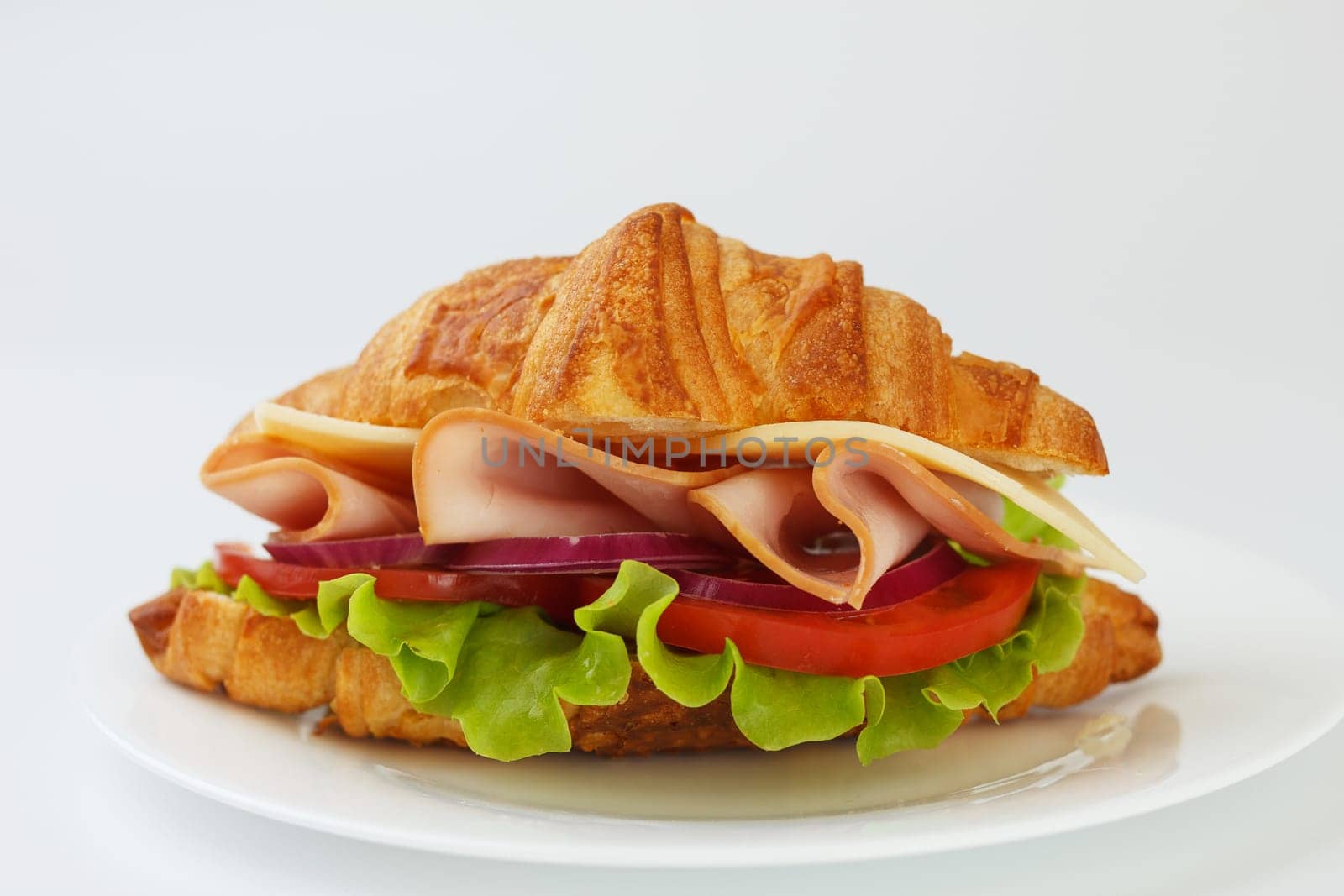 Croissant sandwich with ham, cheese, tomato and lettuce on white background by lara29