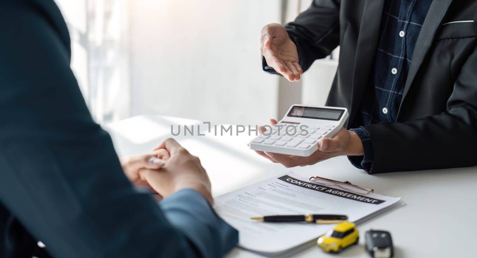 Car Insurance document or lease concept the car broker assisting his customer and explaining the detail of the car contact. Car key Buying or selling signing.