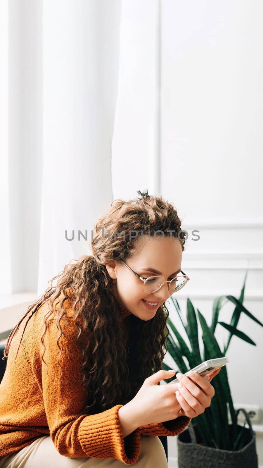 Happy woman browsing modern apps on mobile phone Relaxed woman using cellphone for online shopping. Young woman texting and browsing internet on smartphone At-home relaxation with cellphone technology