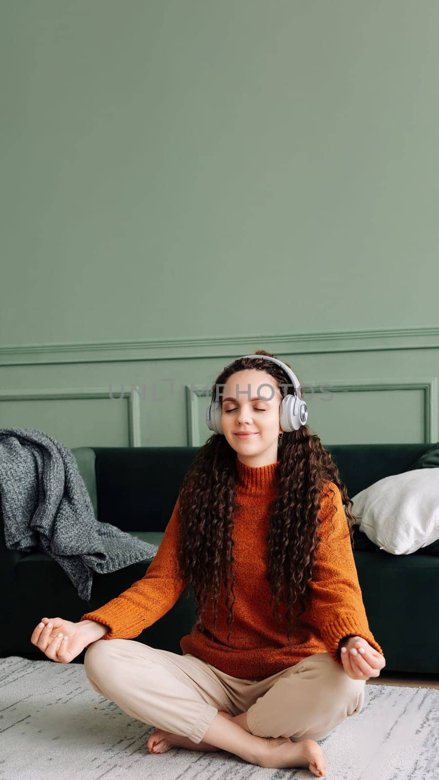 Mindful woman finding inner peace through yoga and meditation with calming music and podcasts. Relaxing at home with yoga and meditation: young woman finding mental balance.