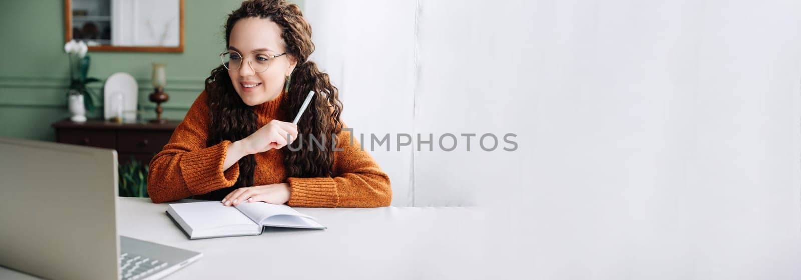 Young Woman Learning and Working Remotely from Home Office with Laptop Computer. Beautiful Young Professional Multi-Tasking with Laptop for Remote Learning and Work.