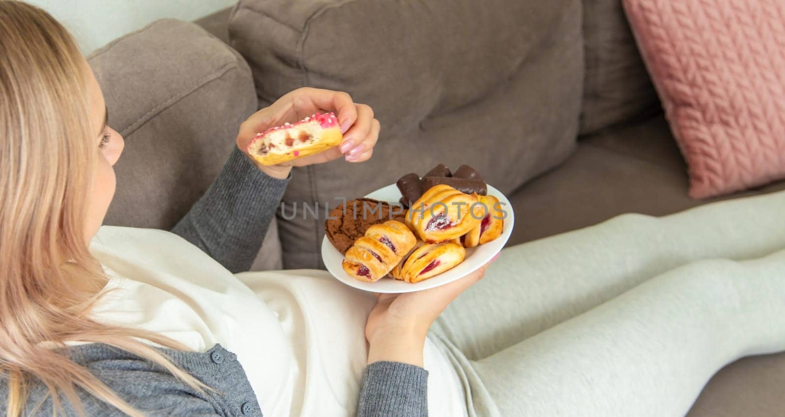 A pregnant woman eats a sweet donut. Selective focus. Food.