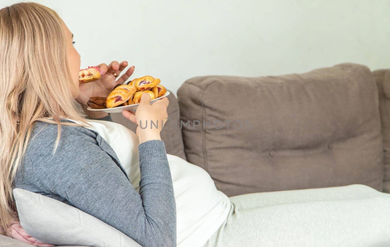 A pregnant woman eats a sweet donut. Selective focus. Food.